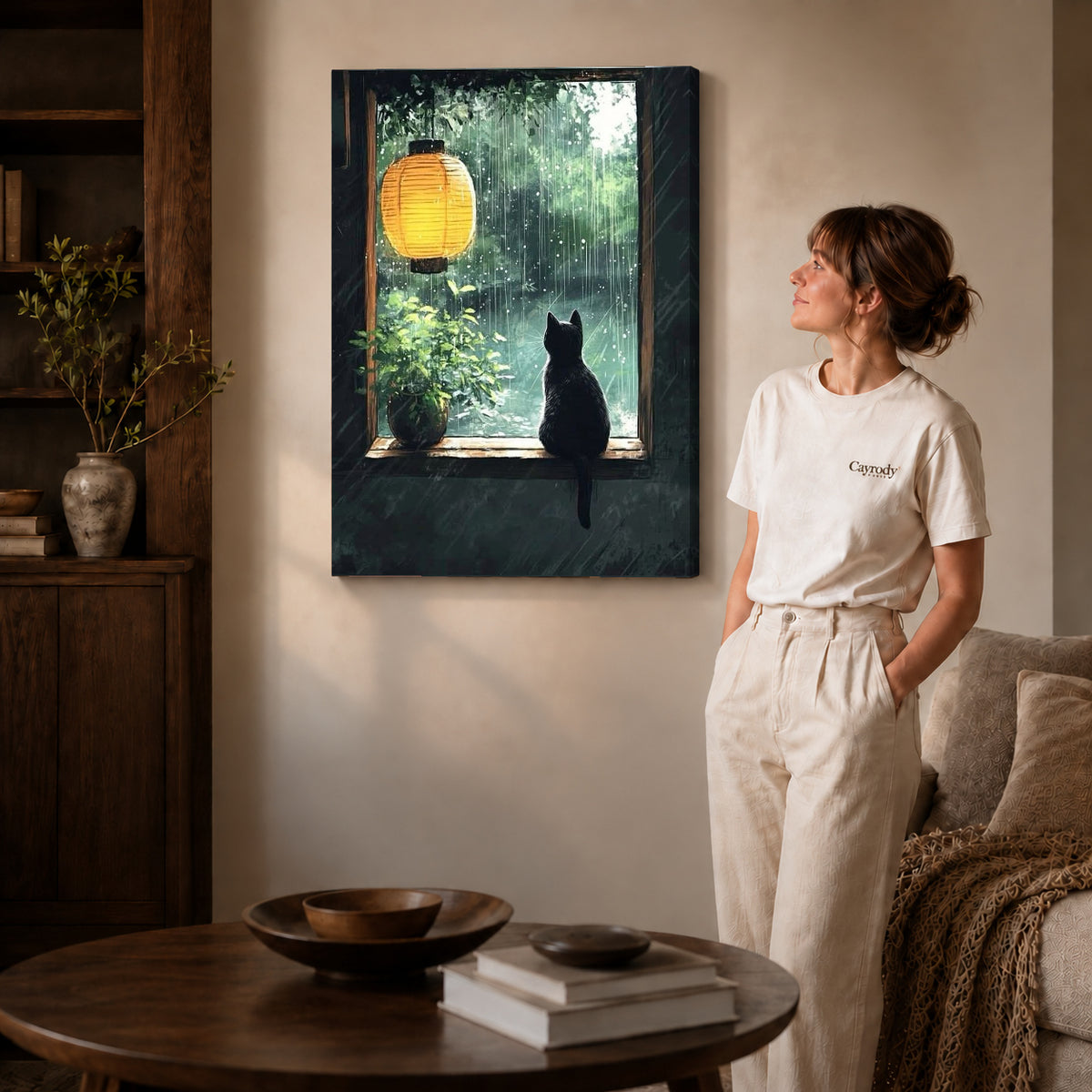 Gallery wrapped rainy window cat canvas art with naturally shaded canvas edges beside a woman wearing cream clothing.