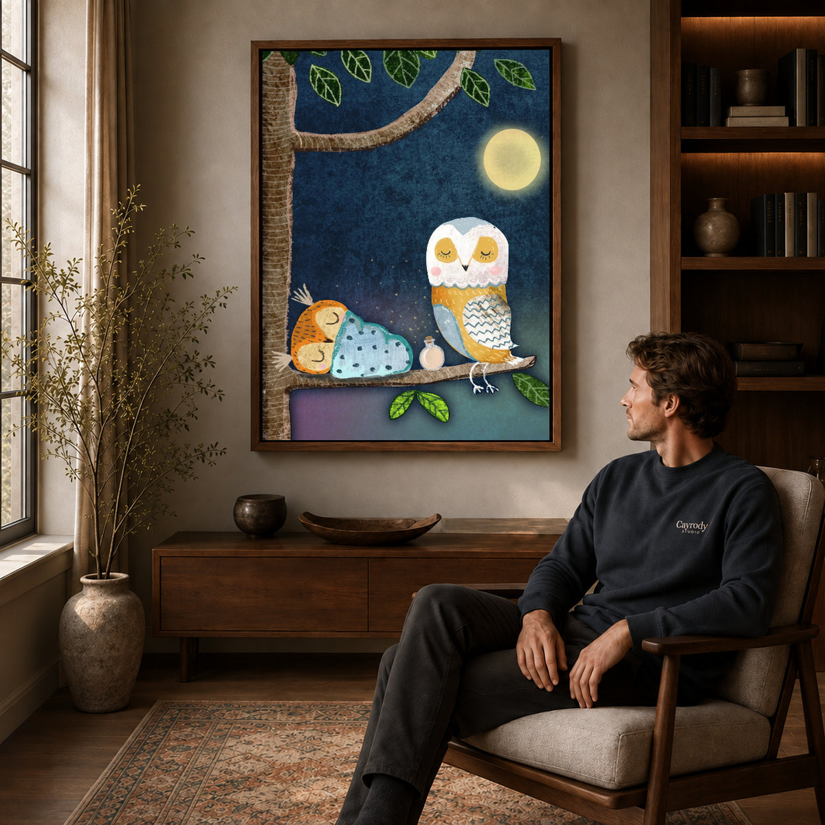 Walnut framed moonlit owl family artwork above a seated man in a wood furnished living room.