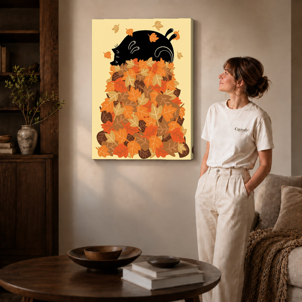Gallery wrapped autumn leaf cat artwork with shaded canvas edges beside a woman wearing cream clothing.