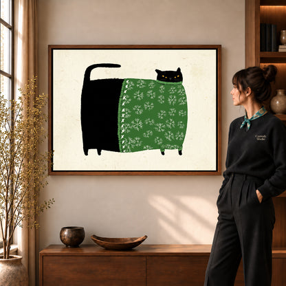 Snowflake Sweater Cat artwork in a walnut frame beside a standing woman in a warm room.