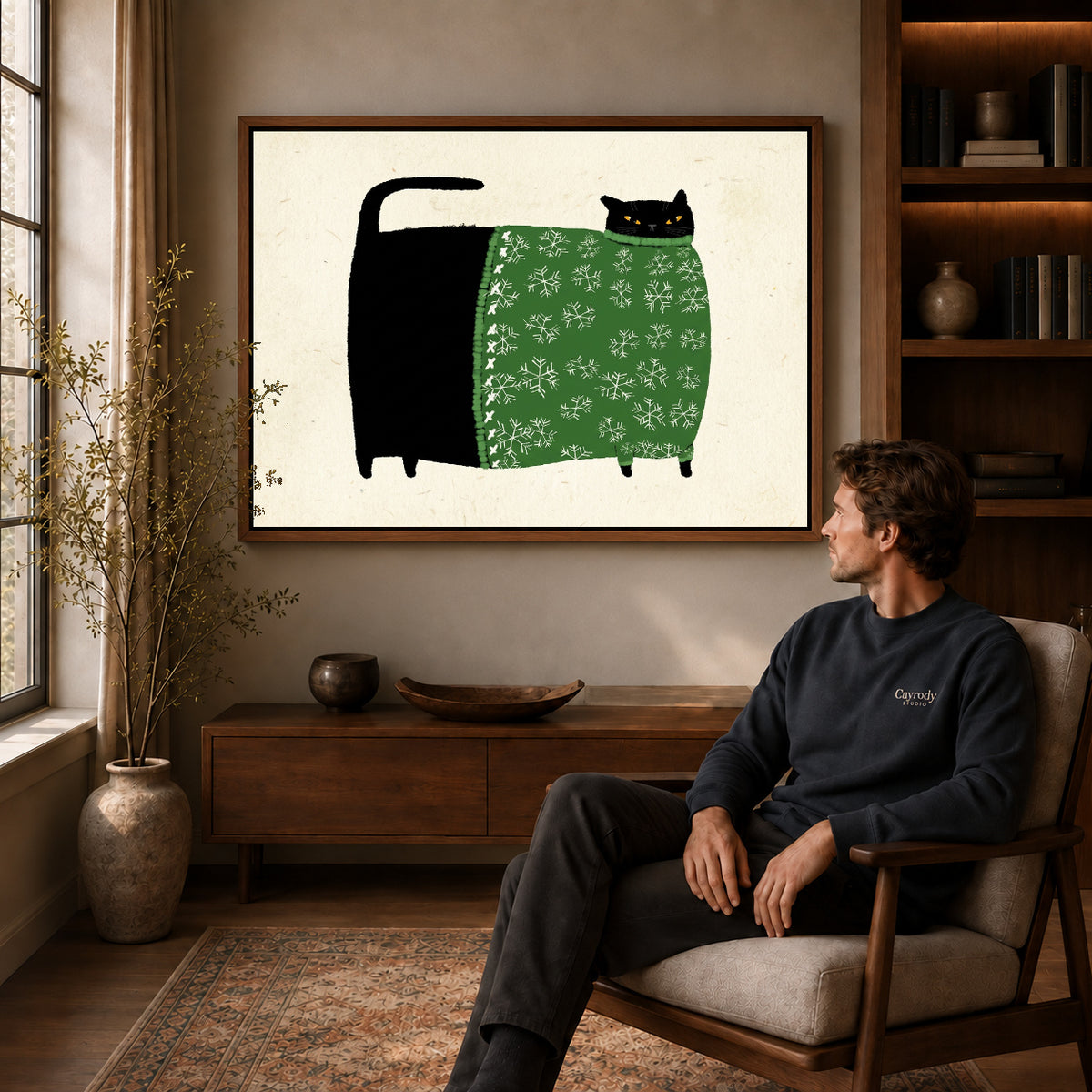 Walnut framed snowflake sweater cat artwork above a seated man in a wood furnished living room.