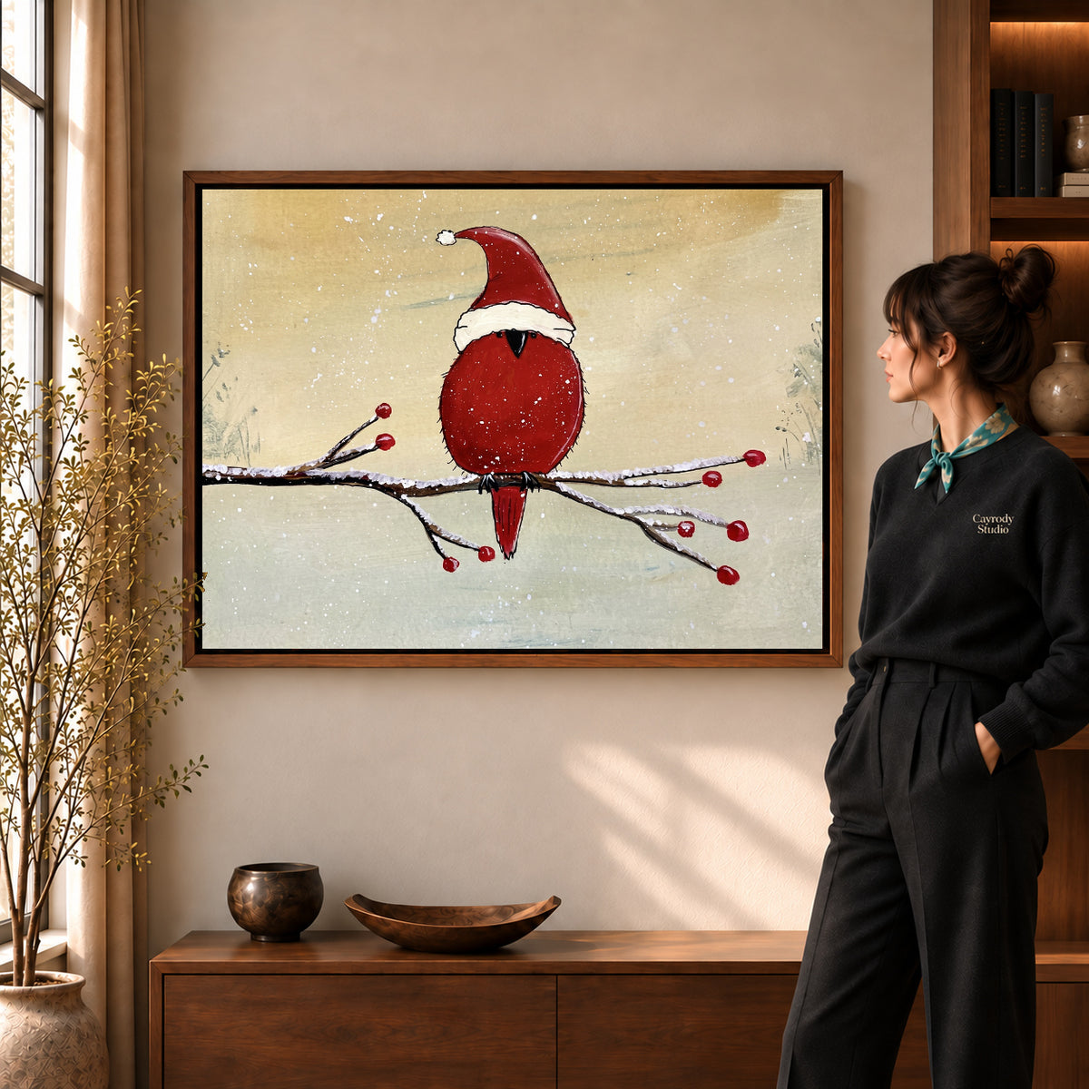 Christmas Cardinal artwork in a walnut frame beside a standing woman in a warm room.