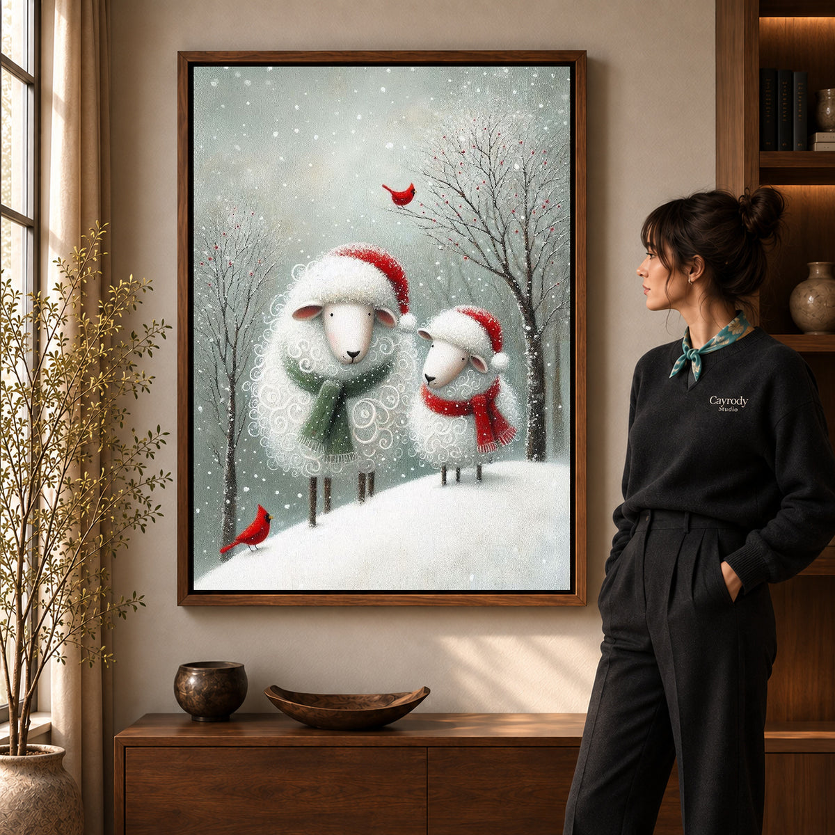Christmas Sheep Pair artwork in a walnut frame beside a standing woman in a warm room.