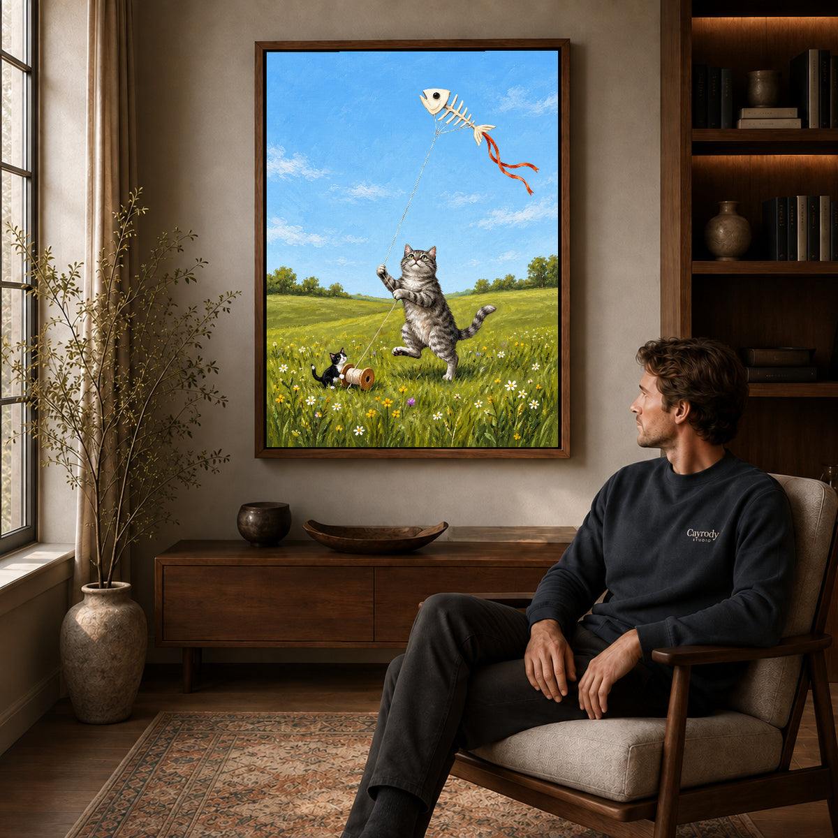 Walnut framed kitten kite friends artwork above a seated man in a wood furnished living room.