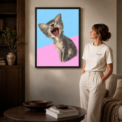 Black framed yawning kitten portrait artwork beside a woman in a warm neutral living room.
