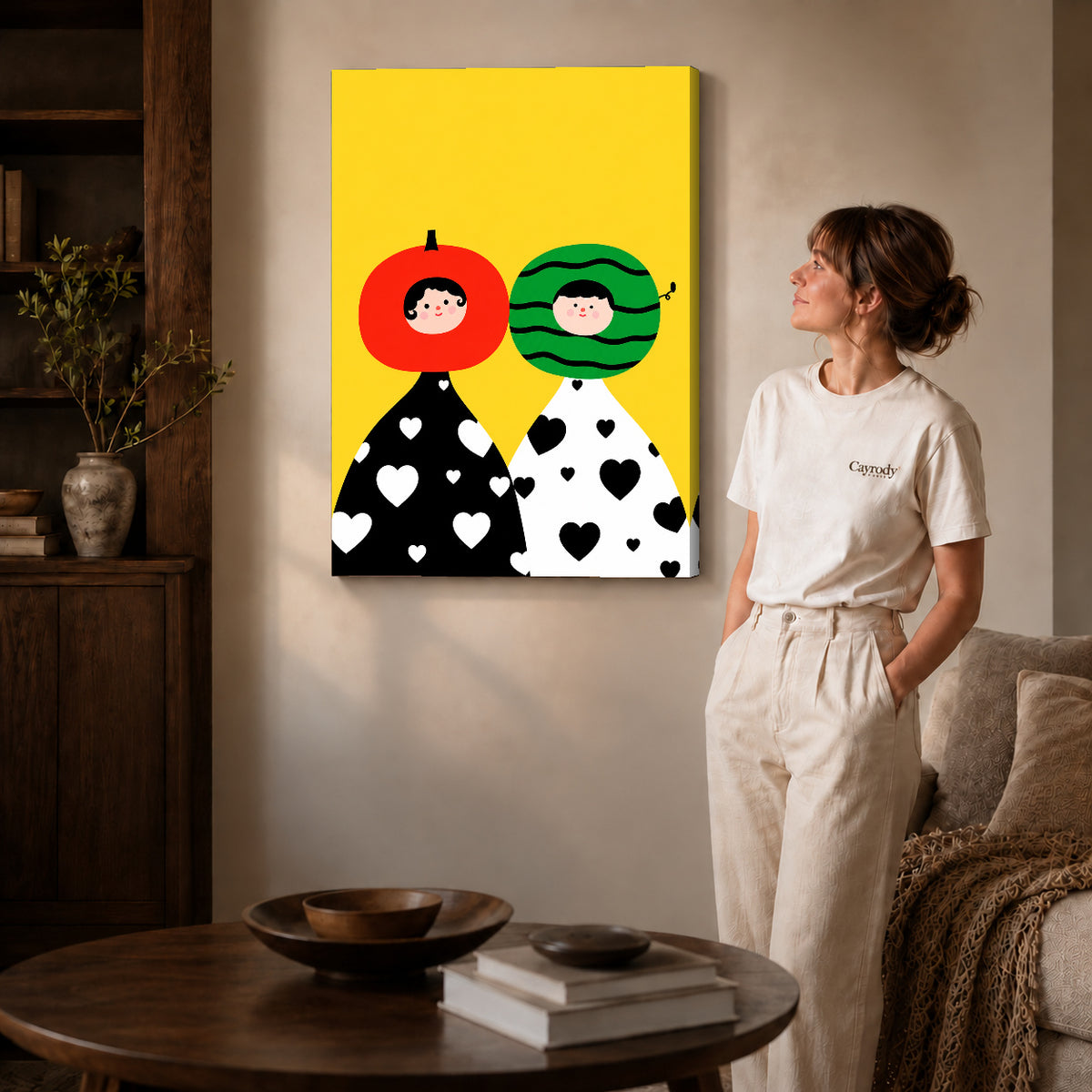 Gallery wrapped fruit head couple artwork with shaded canvas edges beside a woman wearing cream clothing.