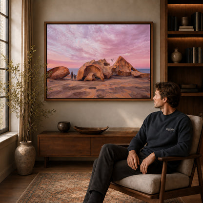 Walnut framed coastal rock sunset artwork above a seated man in a wood furnished living room.