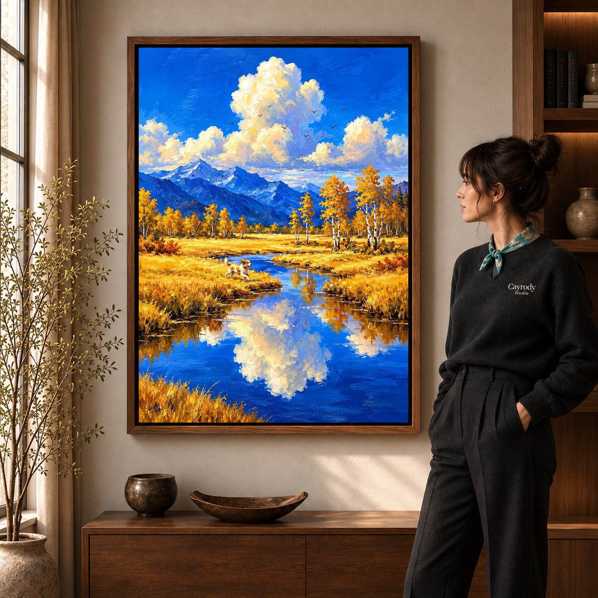 Autumn River Dog artwork in a walnut frame beside a standing woman in a warm room.