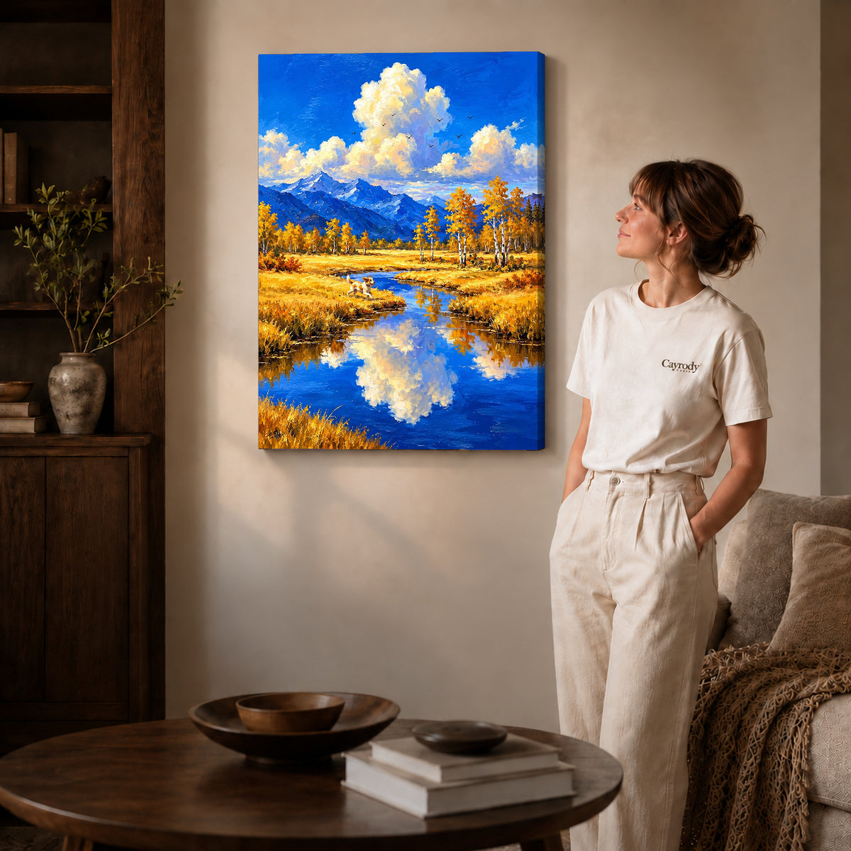 Gallery wrapped autumn river dog artwork with shaded canvas edges beside a woman wearing cream clothing.
