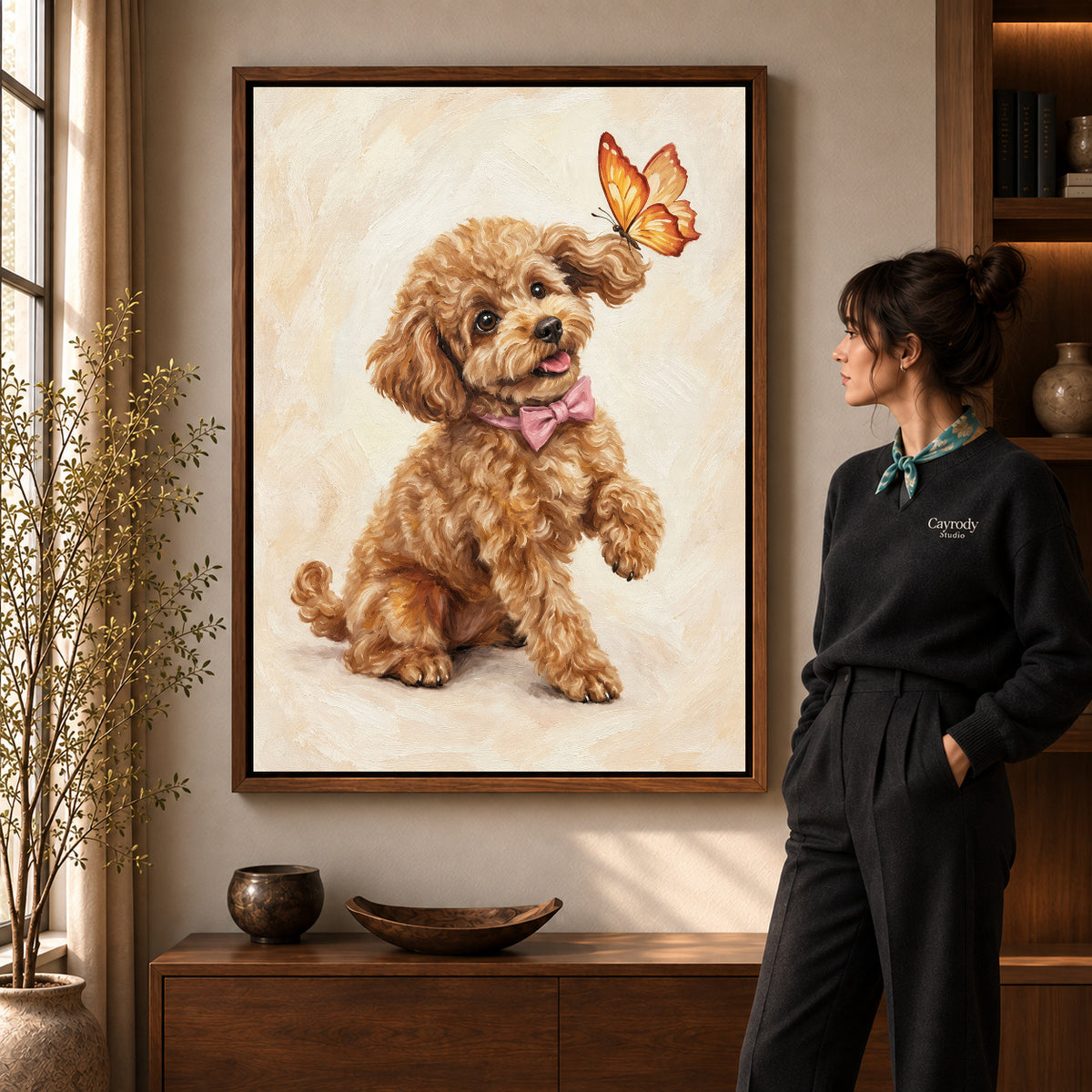 Poodle Butterfly Friend artwork in a walnut frame beside a standing woman in a warm room.