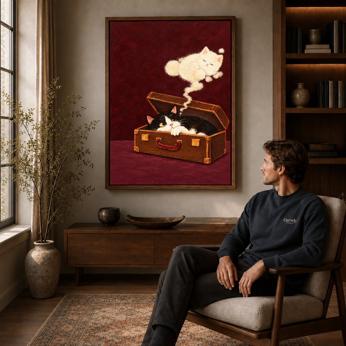 Walnut framed suitcase dream kitten artwork above a seated man in a wood furnished living room.