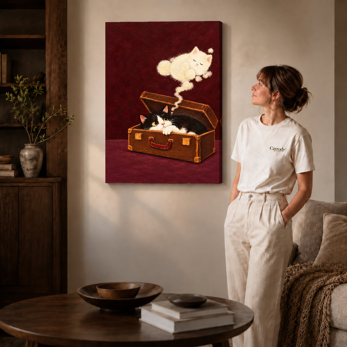 Gallery wrapped suitcase dream kitten artwork with shaded canvas edges beside a woman wearing cream clothing.