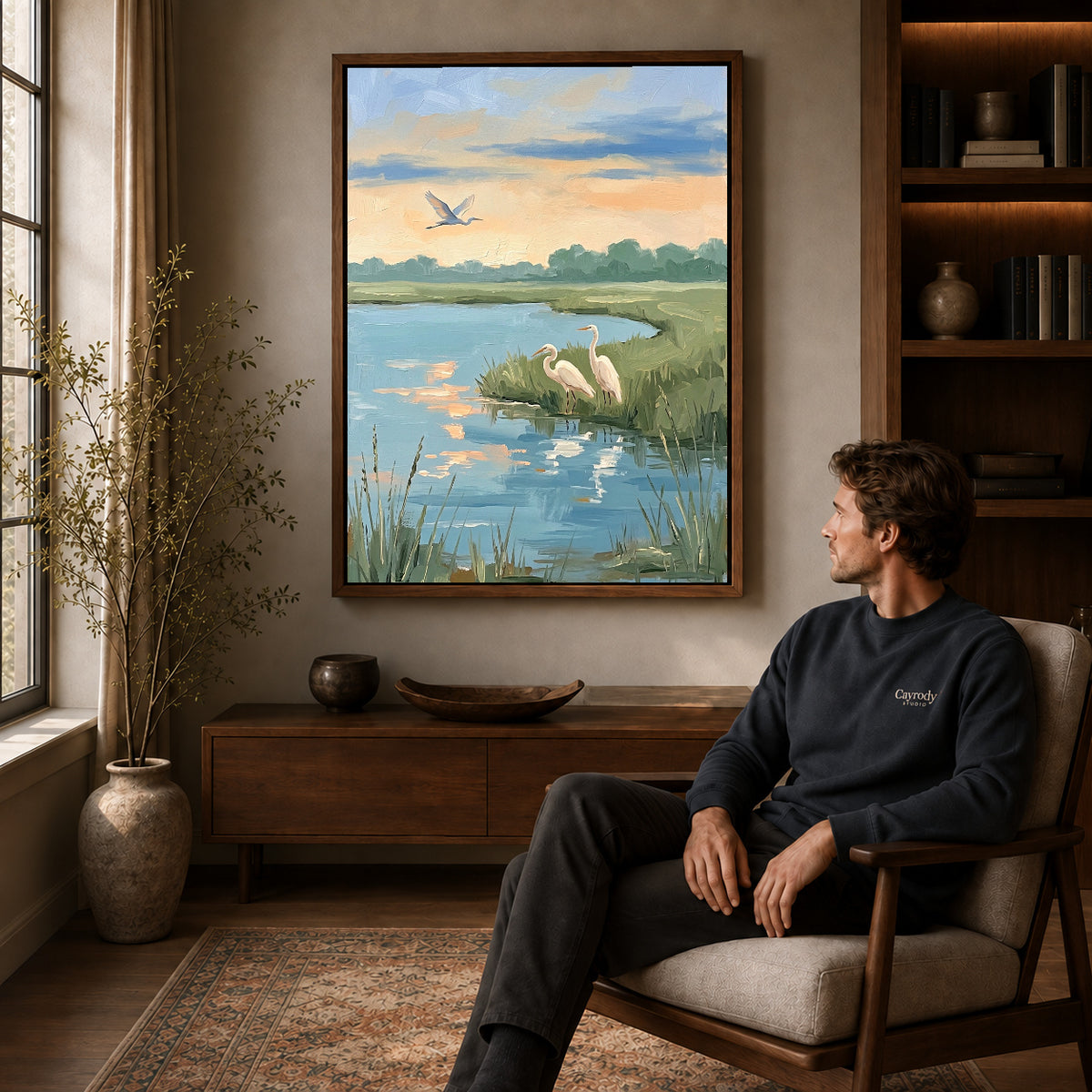 Walnut framed quiet marsh herons artwork above a seated man in a wood furnished living room.