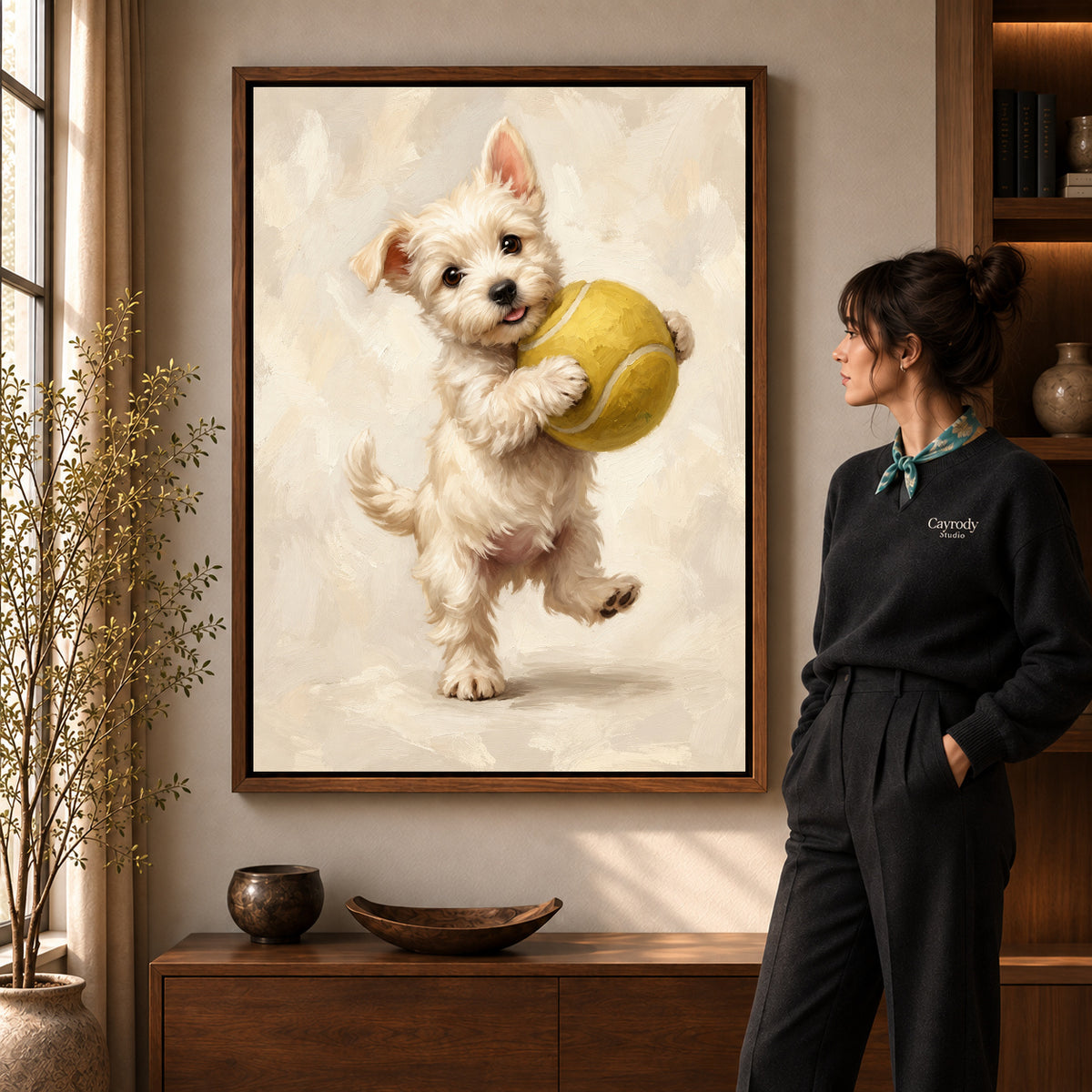 Tennis Ball Puppy artwork in a walnut frame beside a standing woman in a warm room.