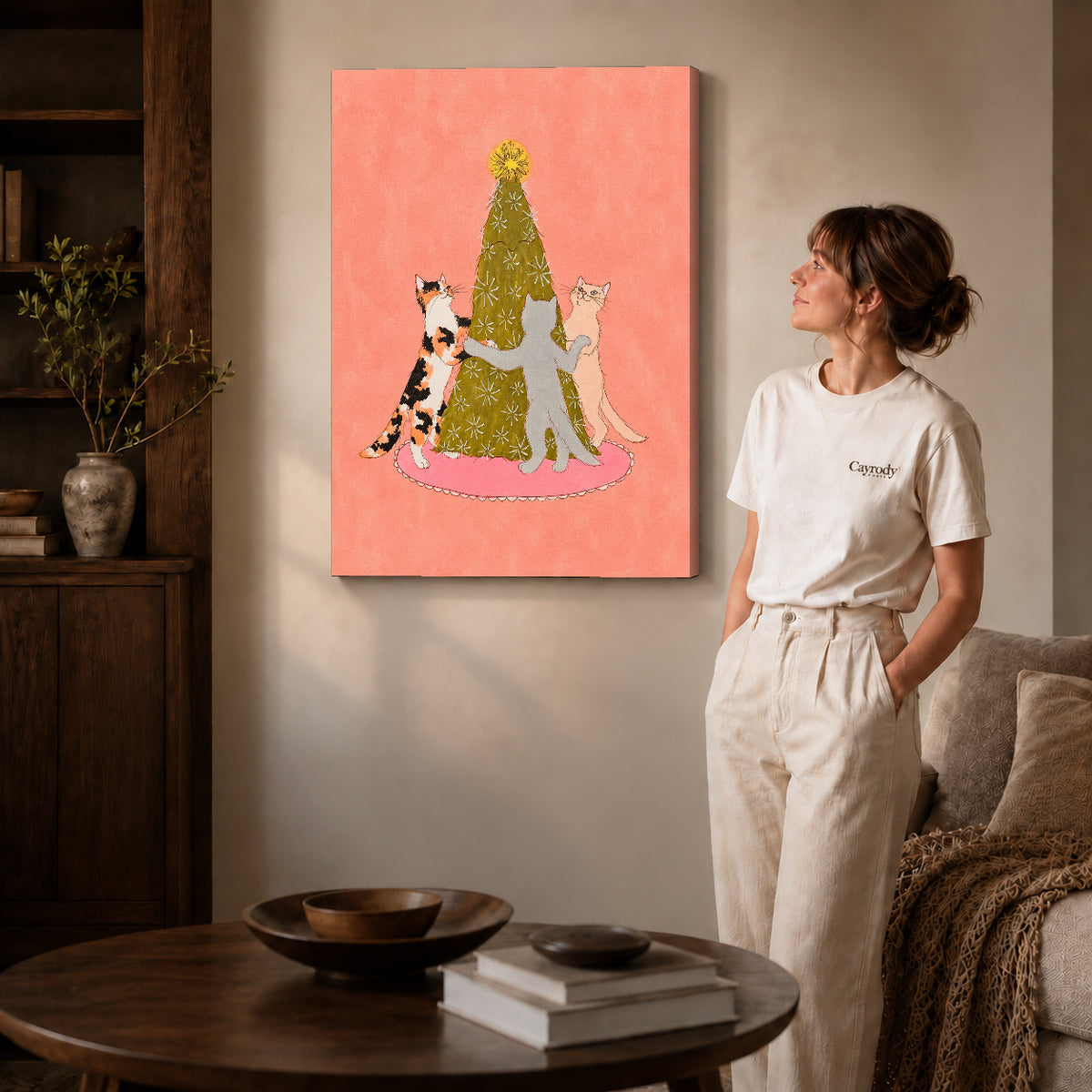Gallery wrapped christmas tree cat dance artwork with shaded canvas edges beside a woman wearing cream clothing.