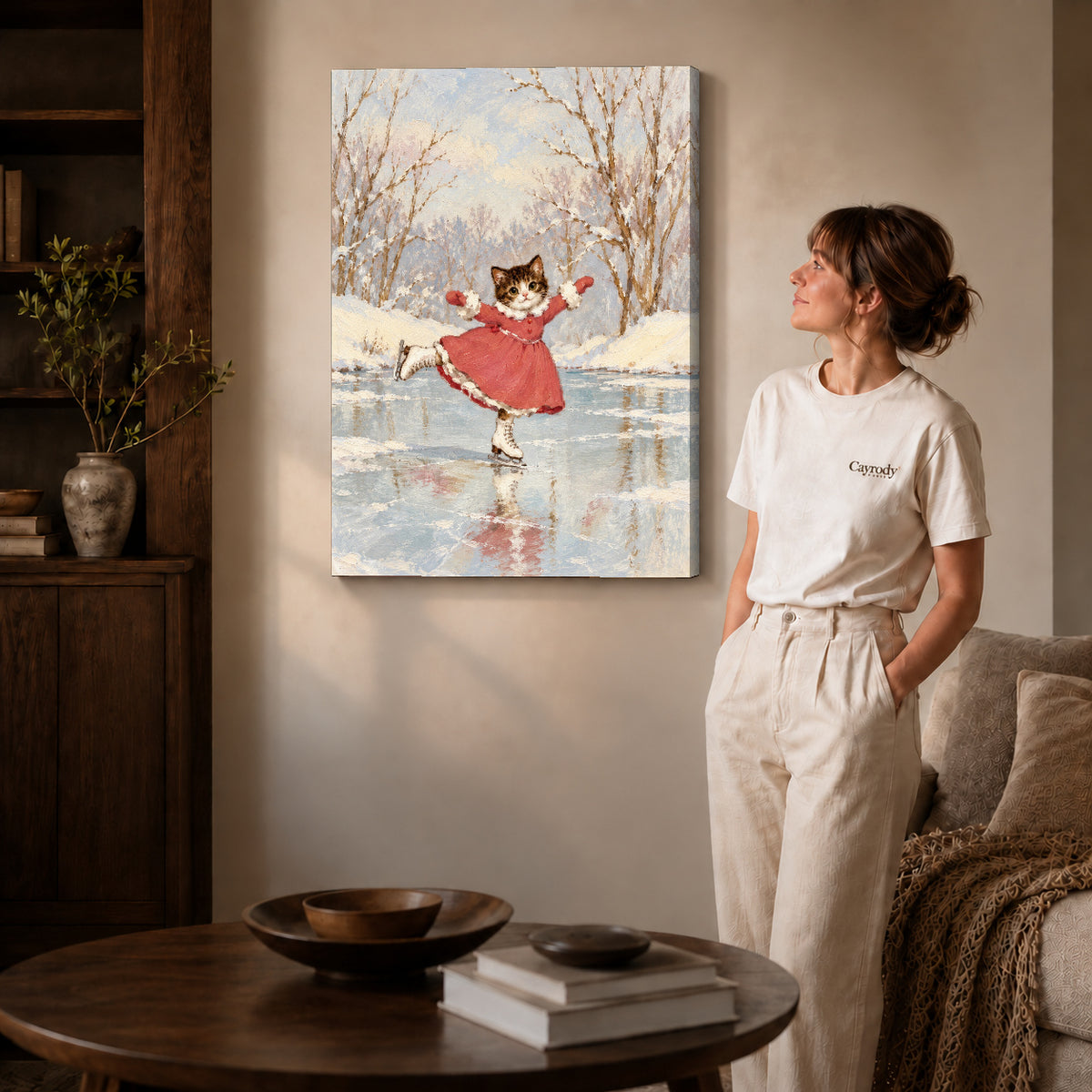 Gallery wrapped winter skating kitten artwork with shaded canvas edges beside a woman wearing cream clothing.