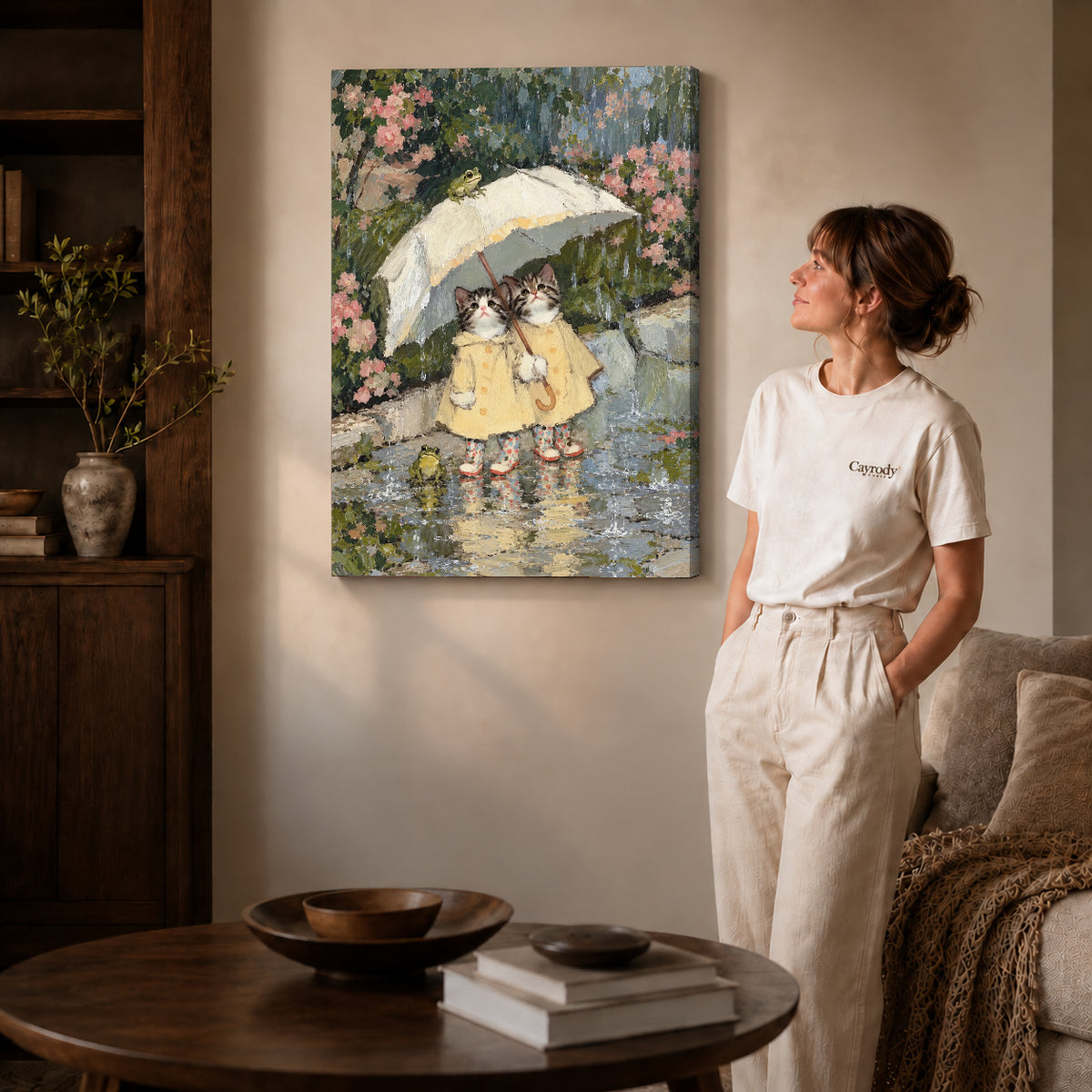 Gallery wrapped raincoat kitten friends artwork with shaded canvas edges beside a woman wearing cream clothing.