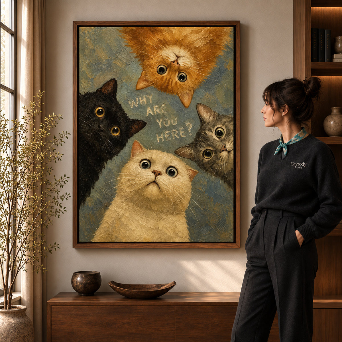 Curious Cat Quartet artwork in a walnut frame beside a standing woman in a warm room.