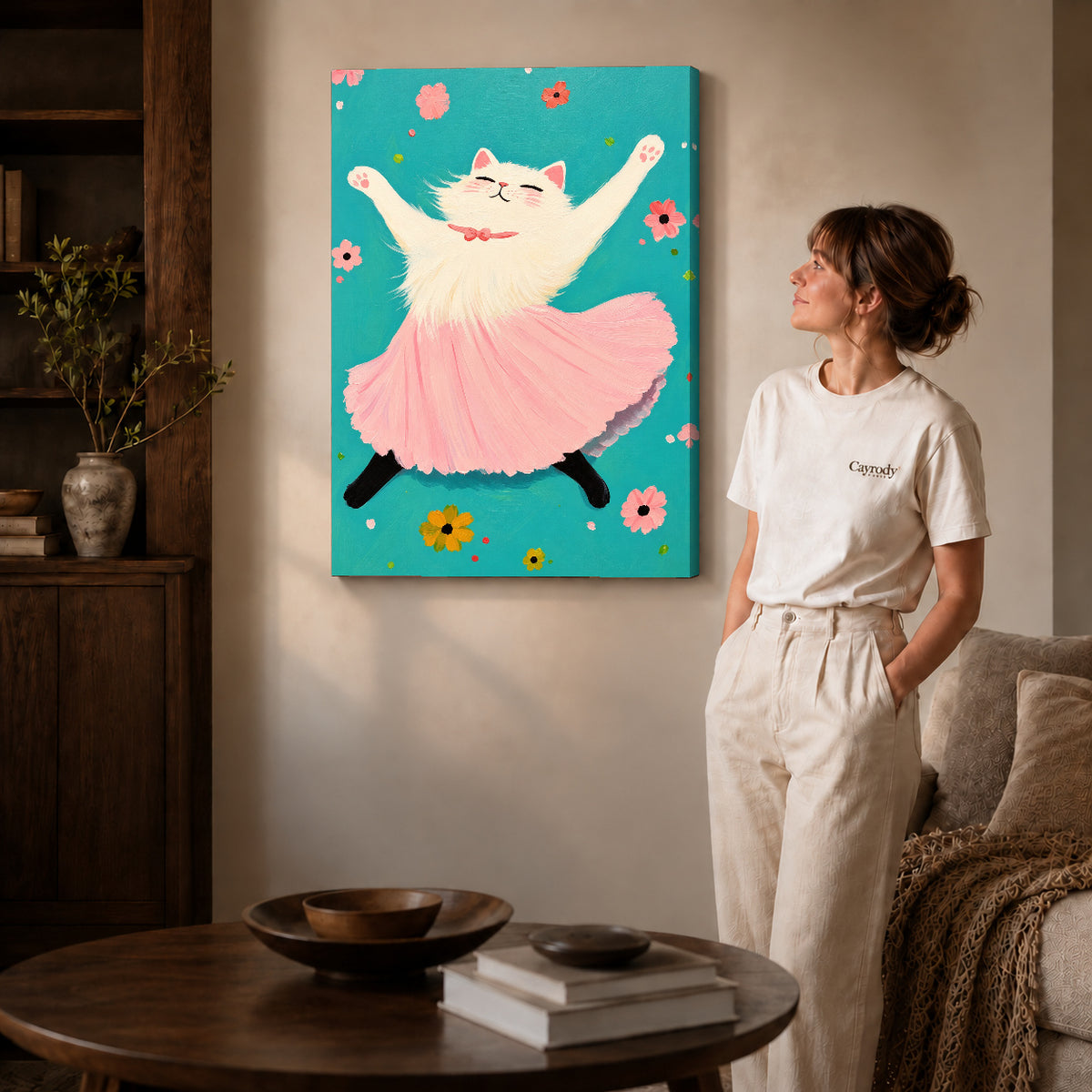 Gallery wrapped joyful ballet cat artwork with shaded canvas edges beside a woman wearing cream clothing.