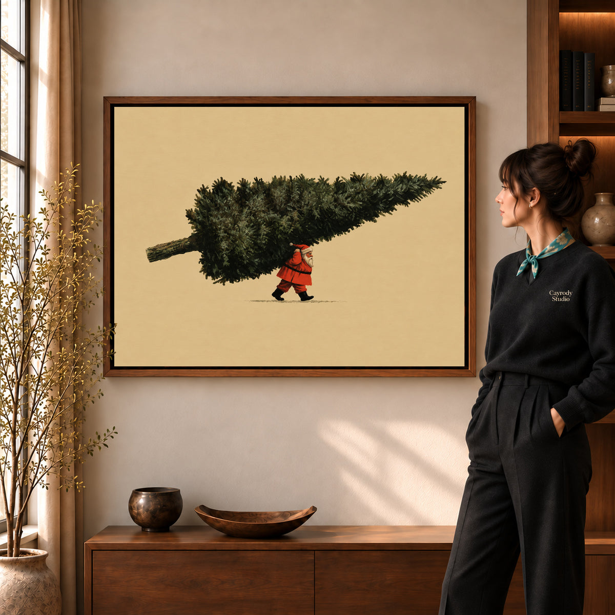 Santa Giant Tree artwork in a walnut frame beside a standing woman in a warm room.