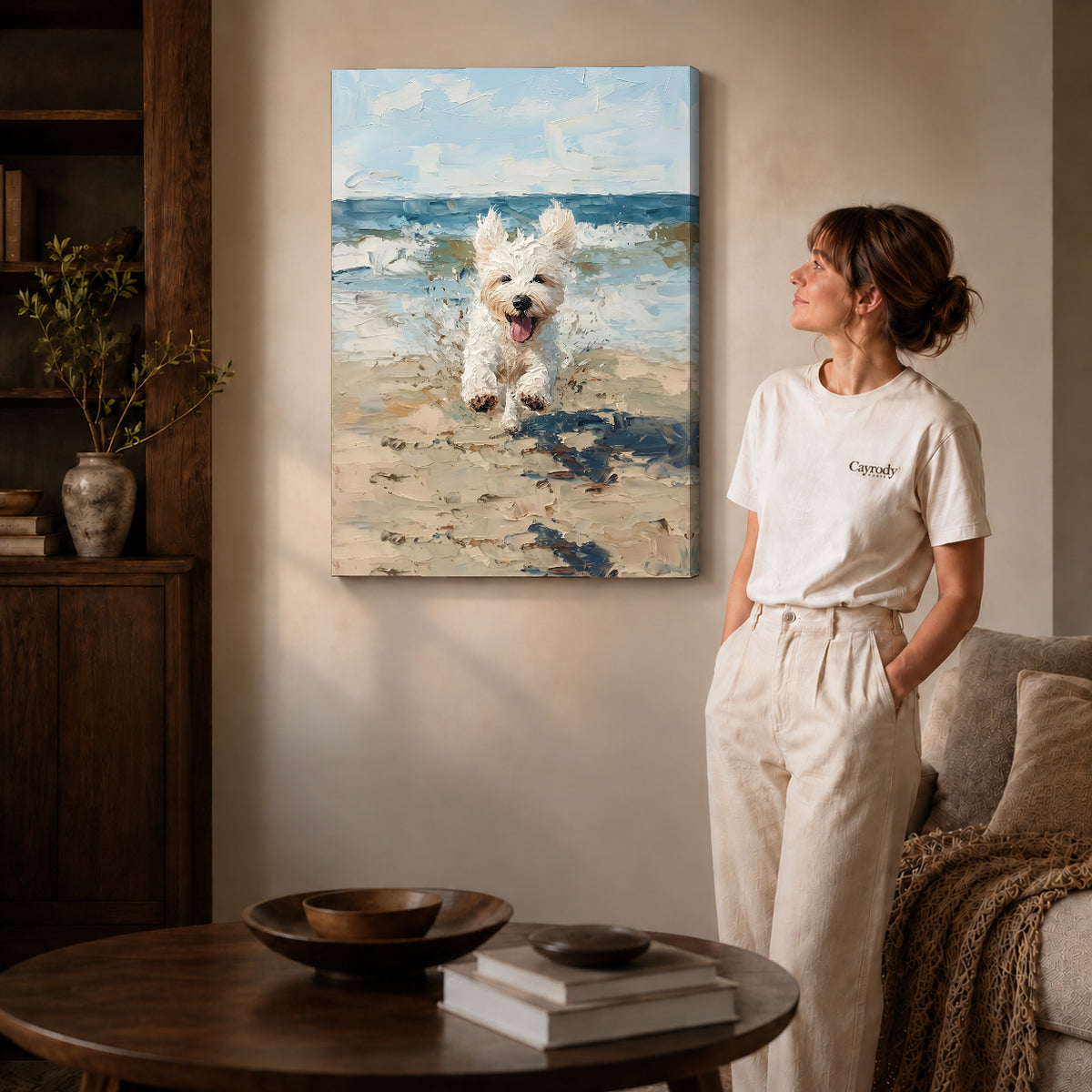 Gallery wrapped seaside jumping puppy artwork with shaded canvas edges beside a woman wearing cream clothing.