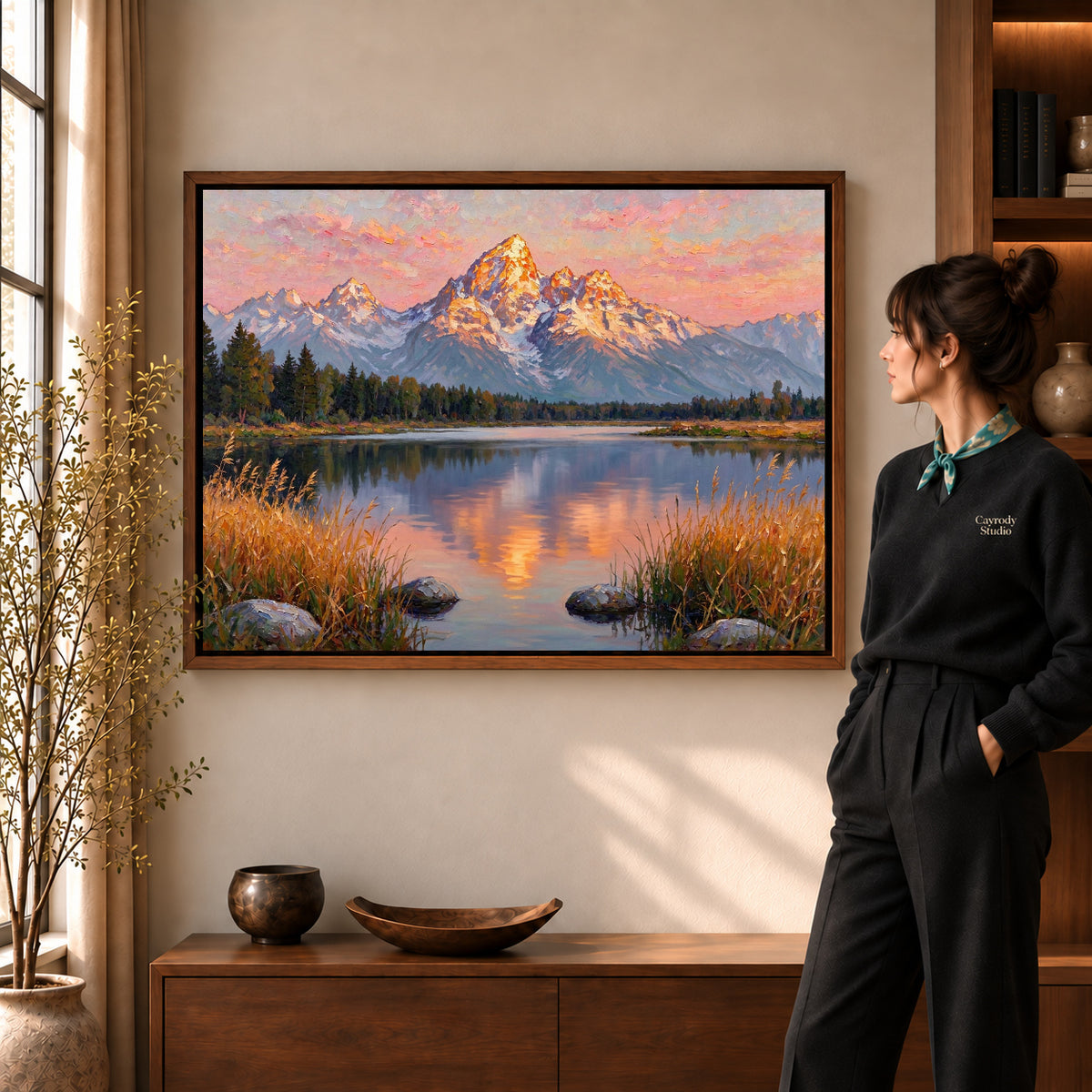 Golden Mountain Reflection artwork in a walnut frame beside a standing woman in a warm room.