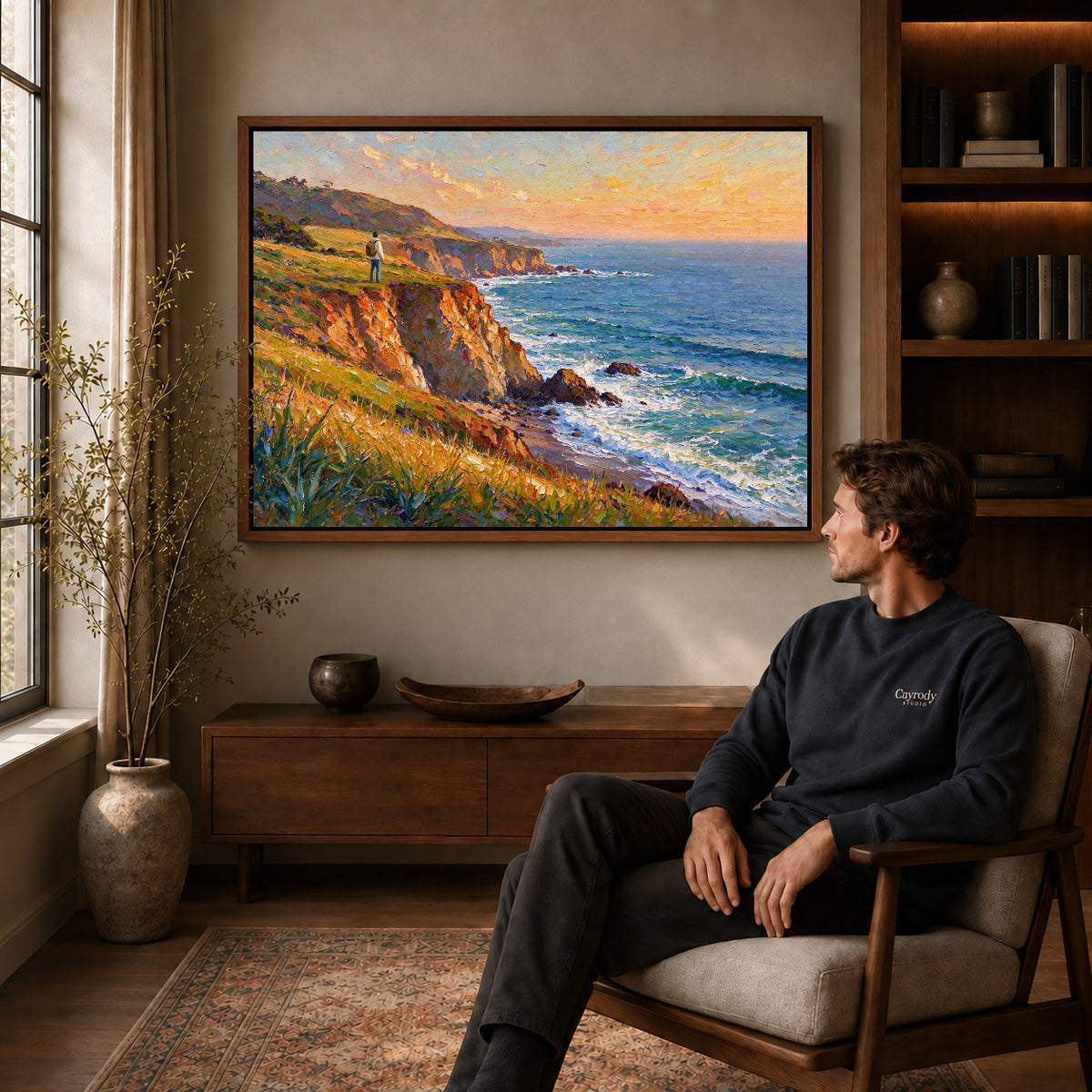 Walnut framed sunset coastal wanderer artwork above a seated man in a wood furnished living room.
