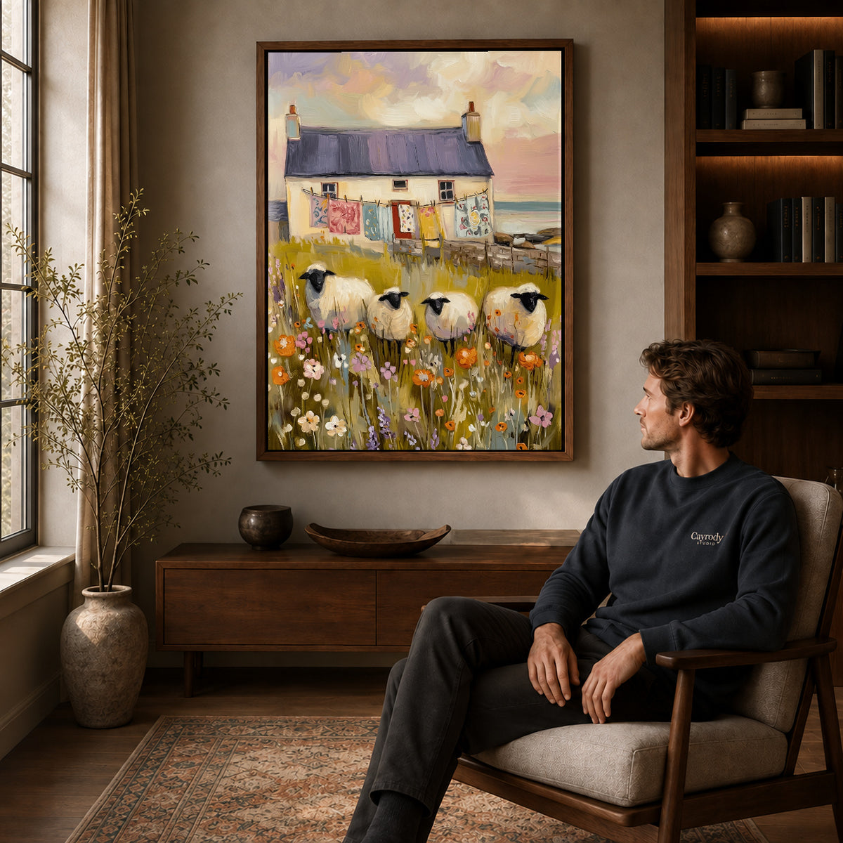 Walnut framed cottage sheep garden artwork above a seated man in a wood furnished living room.