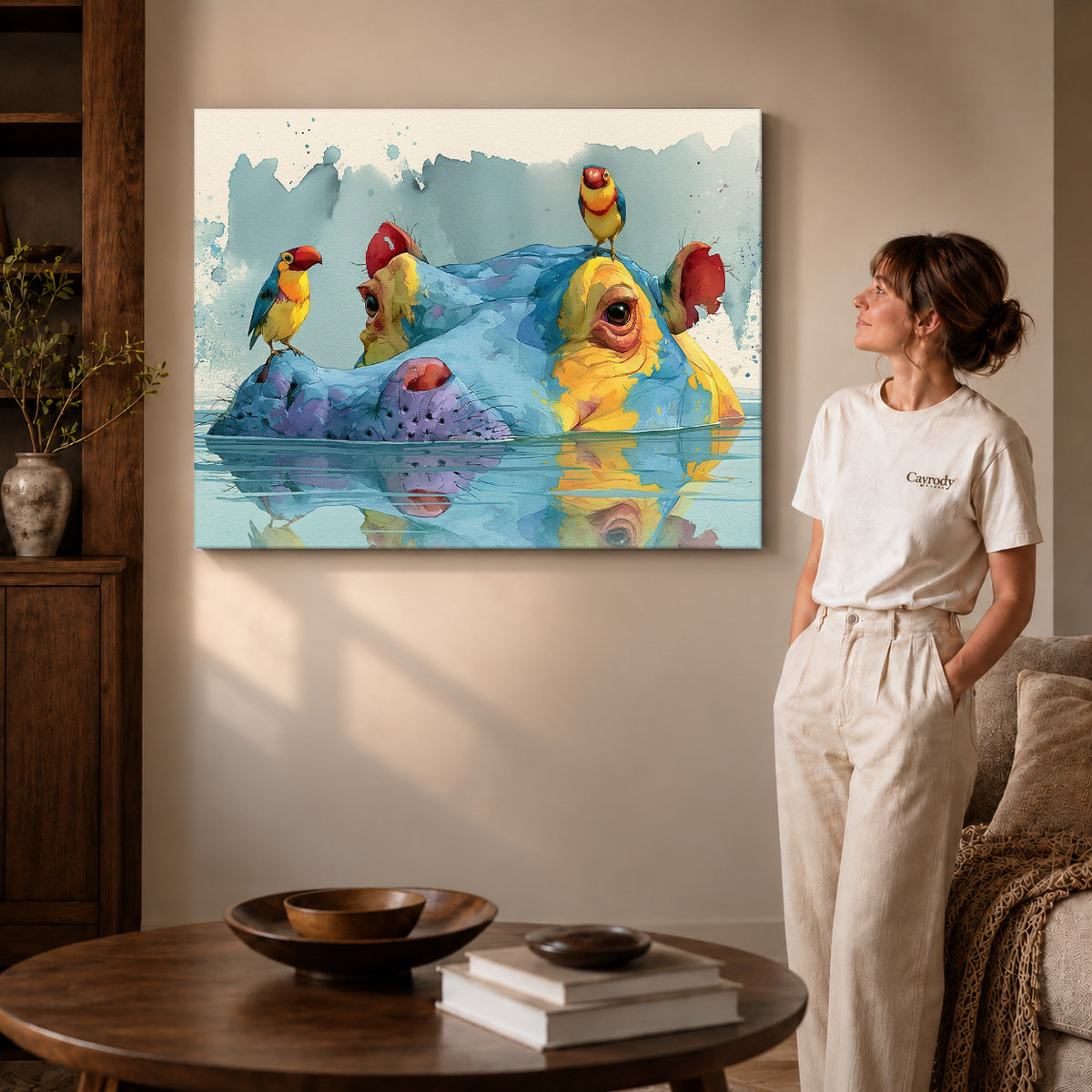 Gallery wrapped hippo bird friends artwork with shaded canvas edges beside a woman wearing cream clothing.