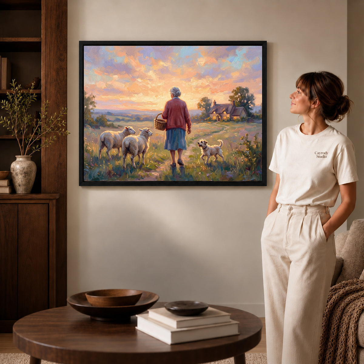 Black framed sunset shepherd home artwork beside a woman in a warm neutral living room.