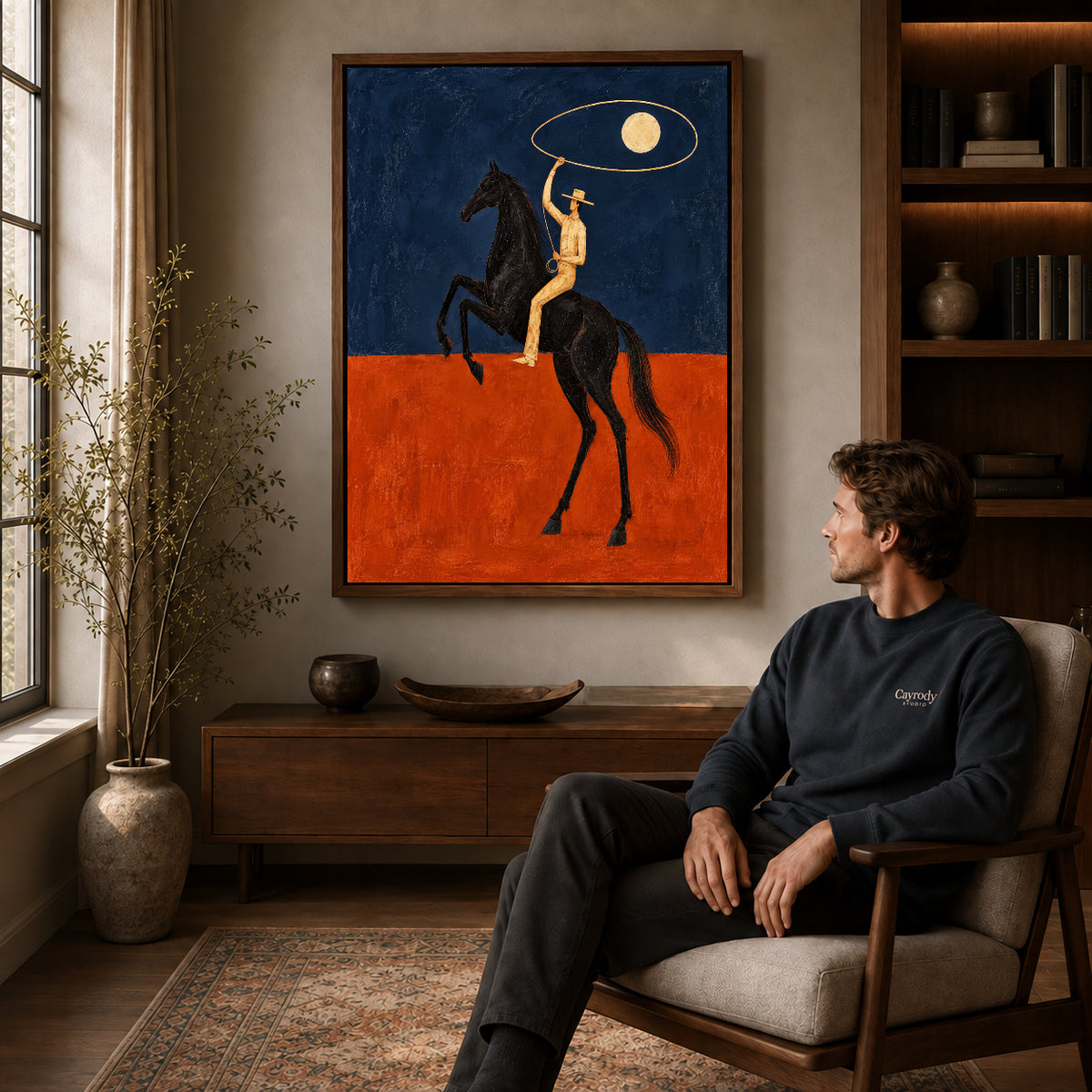 Walnut framed moon lasso rider artwork above a seated man in a wood furnished living room.
