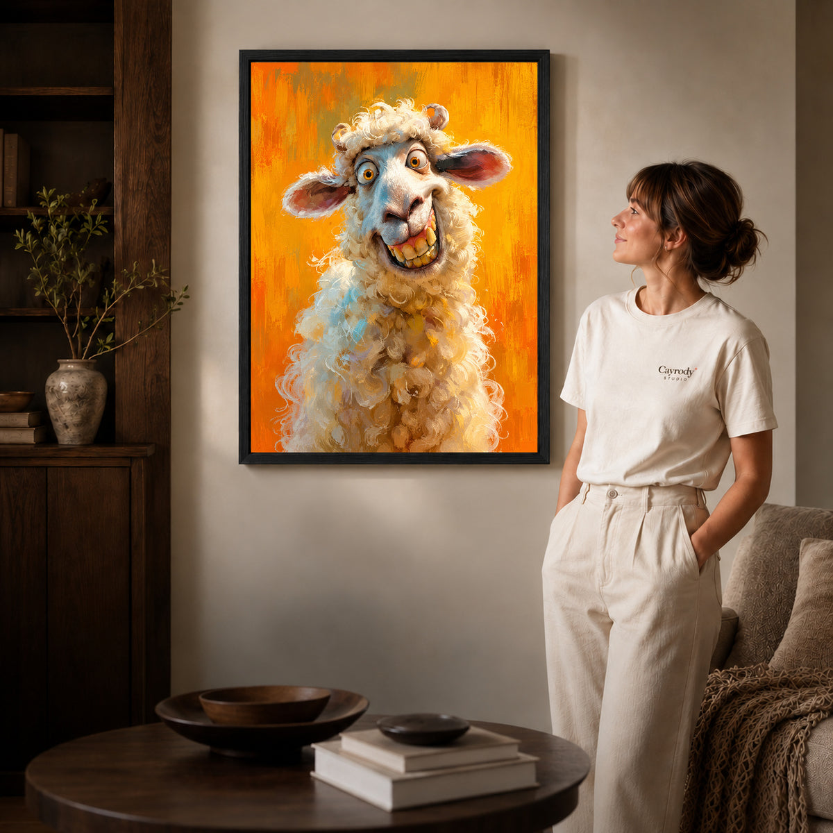 Black framed grinning curly sheep artwork beside a woman in a warm neutral living room.