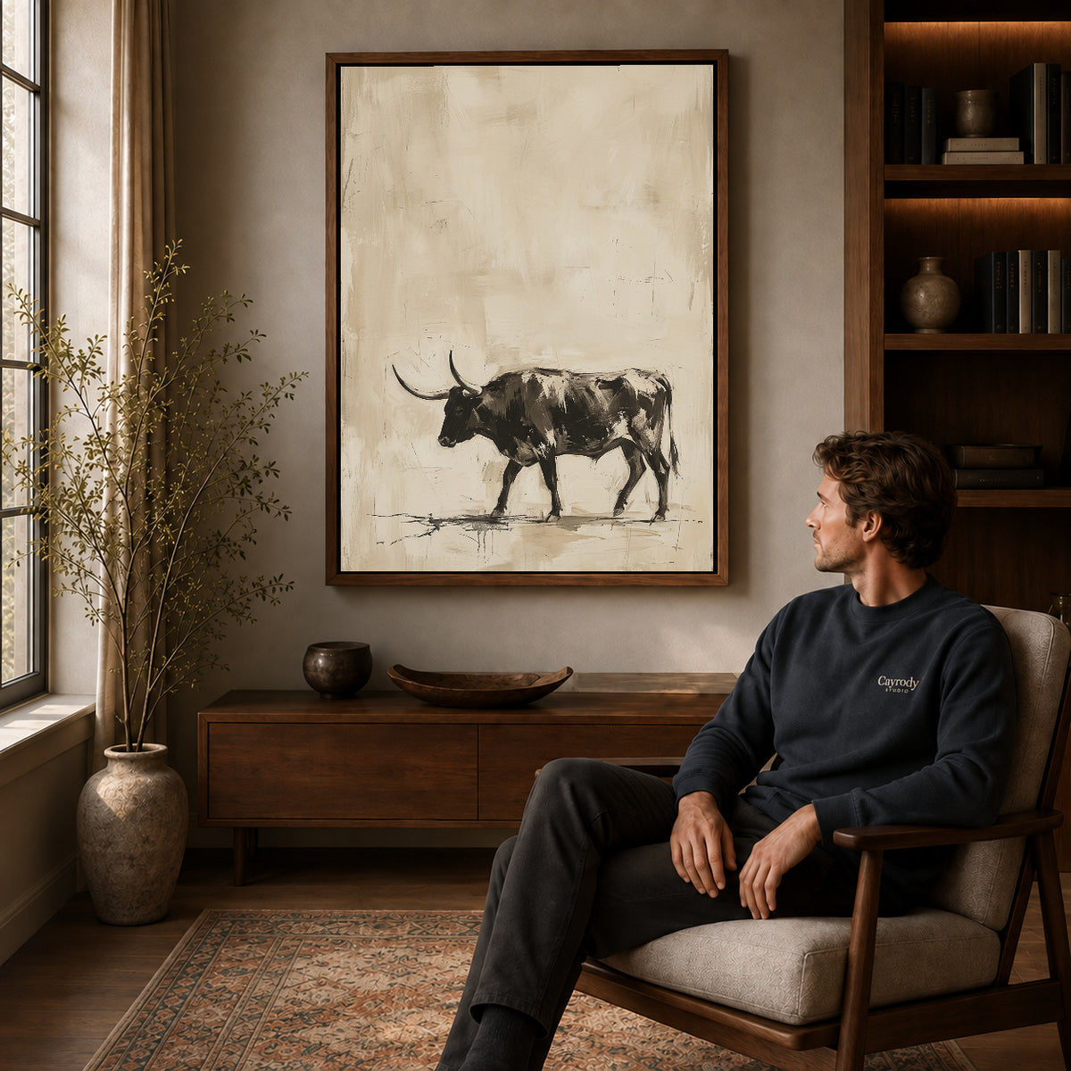 Walnut framed neutral longhorn bull artwork above a seated man in a wood furnished living room.
