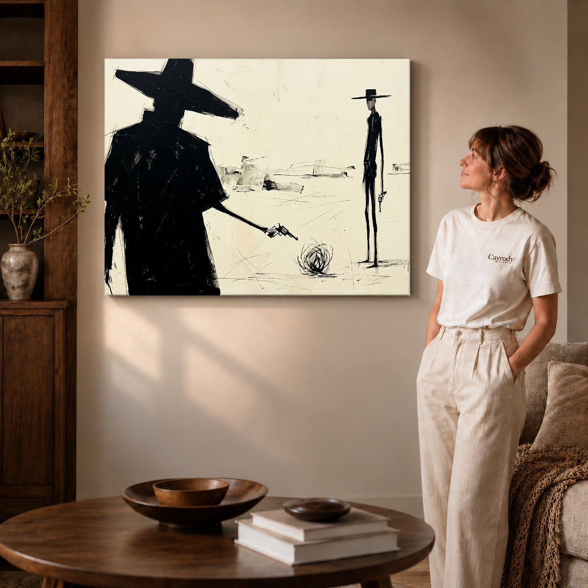 Gallery wrapped western desert standoff artwork with shaded canvas edges beside a woman wearing cream clothing.