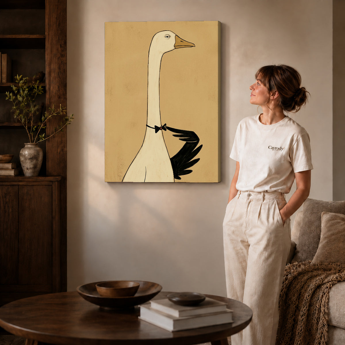 Gallery wrapped elegant bowtie goose artwork with shaded canvas edges beside a woman wearing cream clothing.