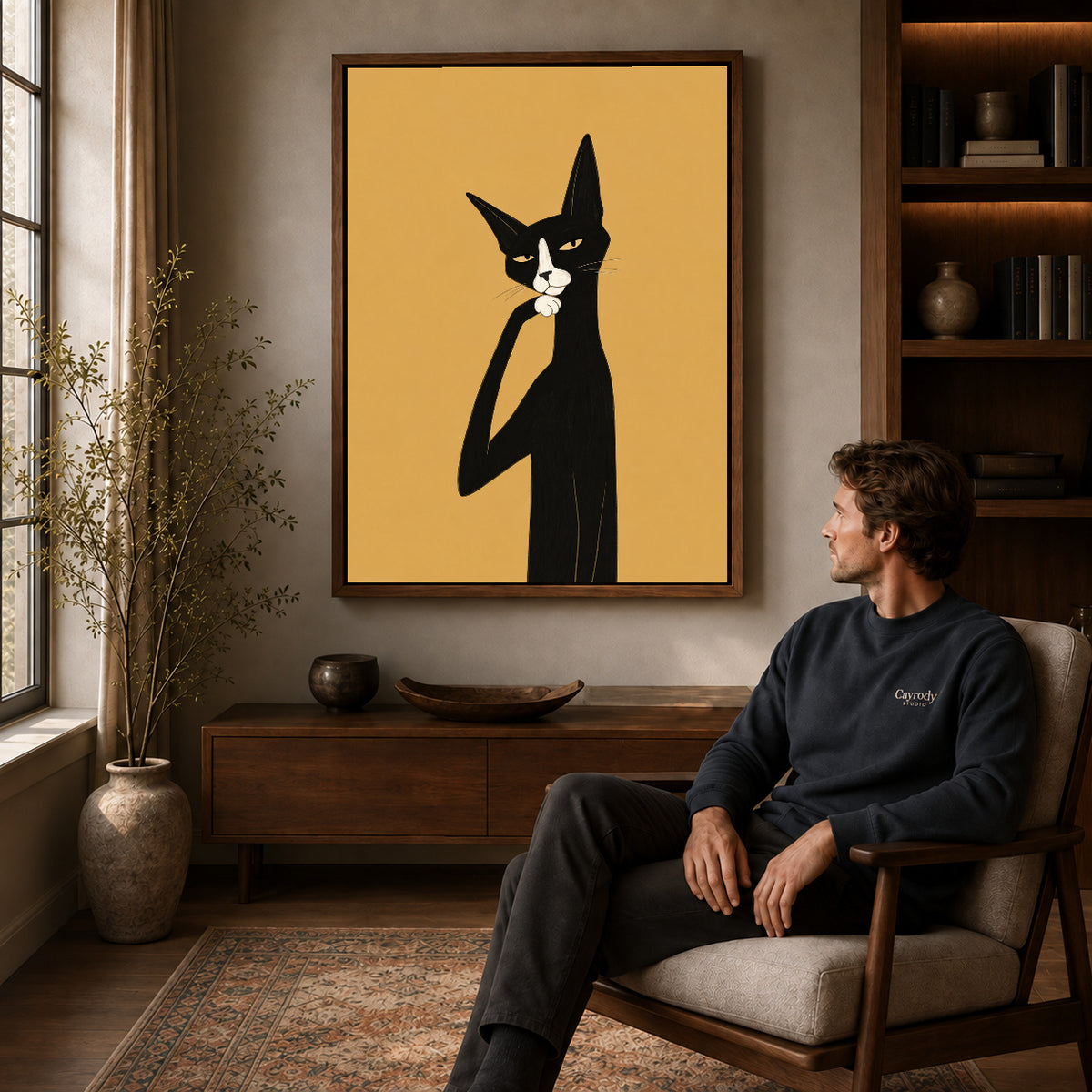 Walnut framed thoughtful tuxedo cat artwork above a seated man in a wood furnished living room.