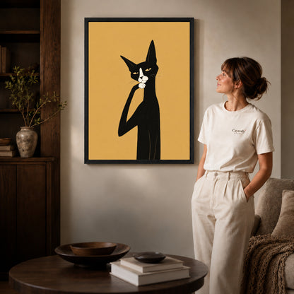 Black framed thoughtful tuxedo cat artwork beside a woman in a warm neutral living room.