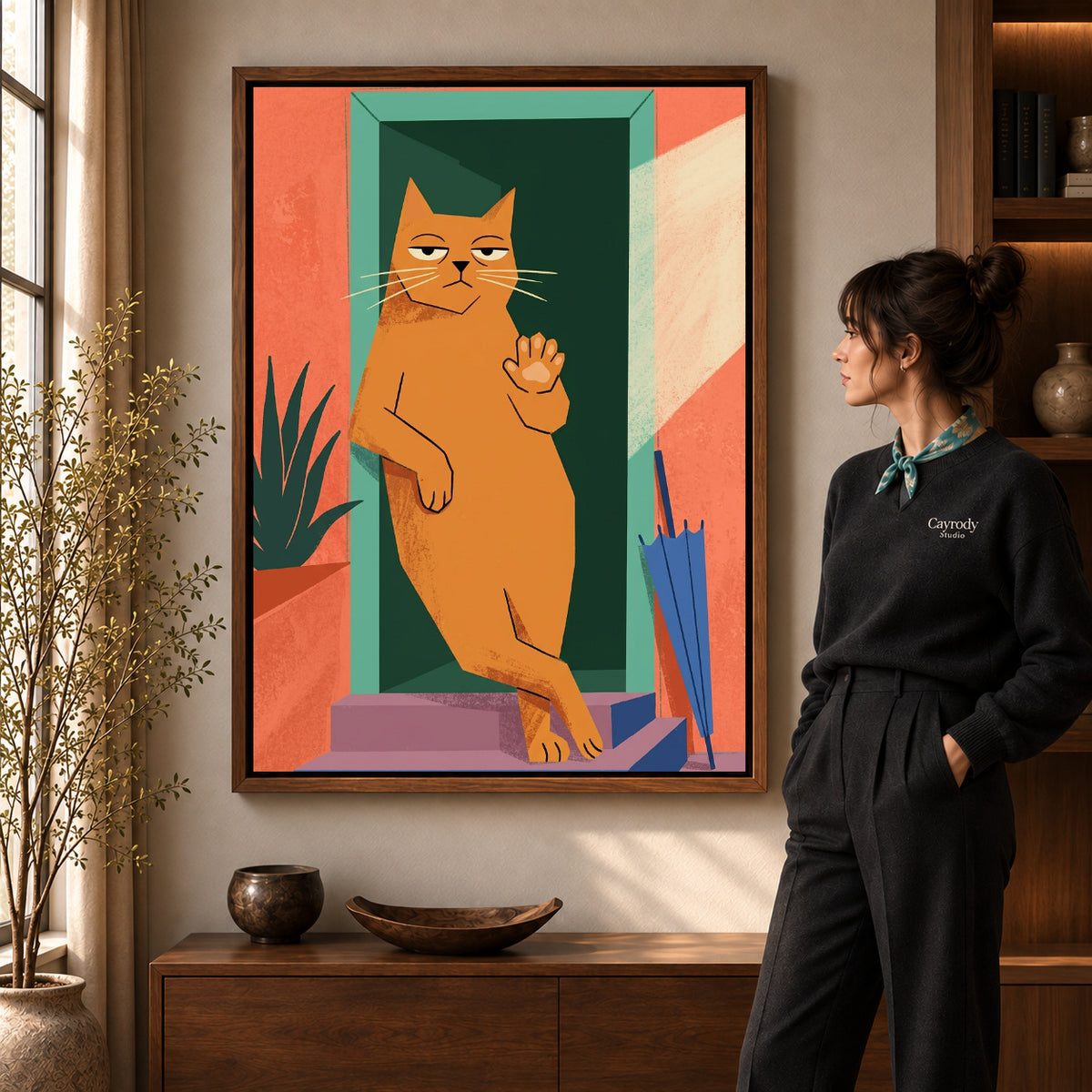 Doorway Greeting Cat artwork in a walnut frame beside a standing woman in a warm room.