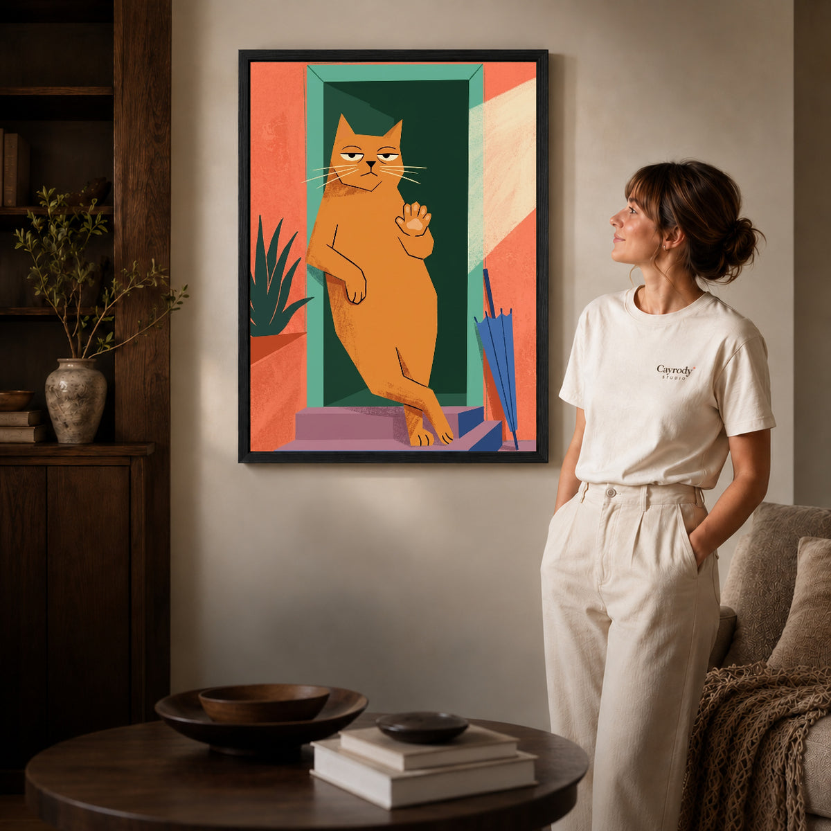 Black framed doorway greeting cat artwork beside a woman in a warm neutral living room.