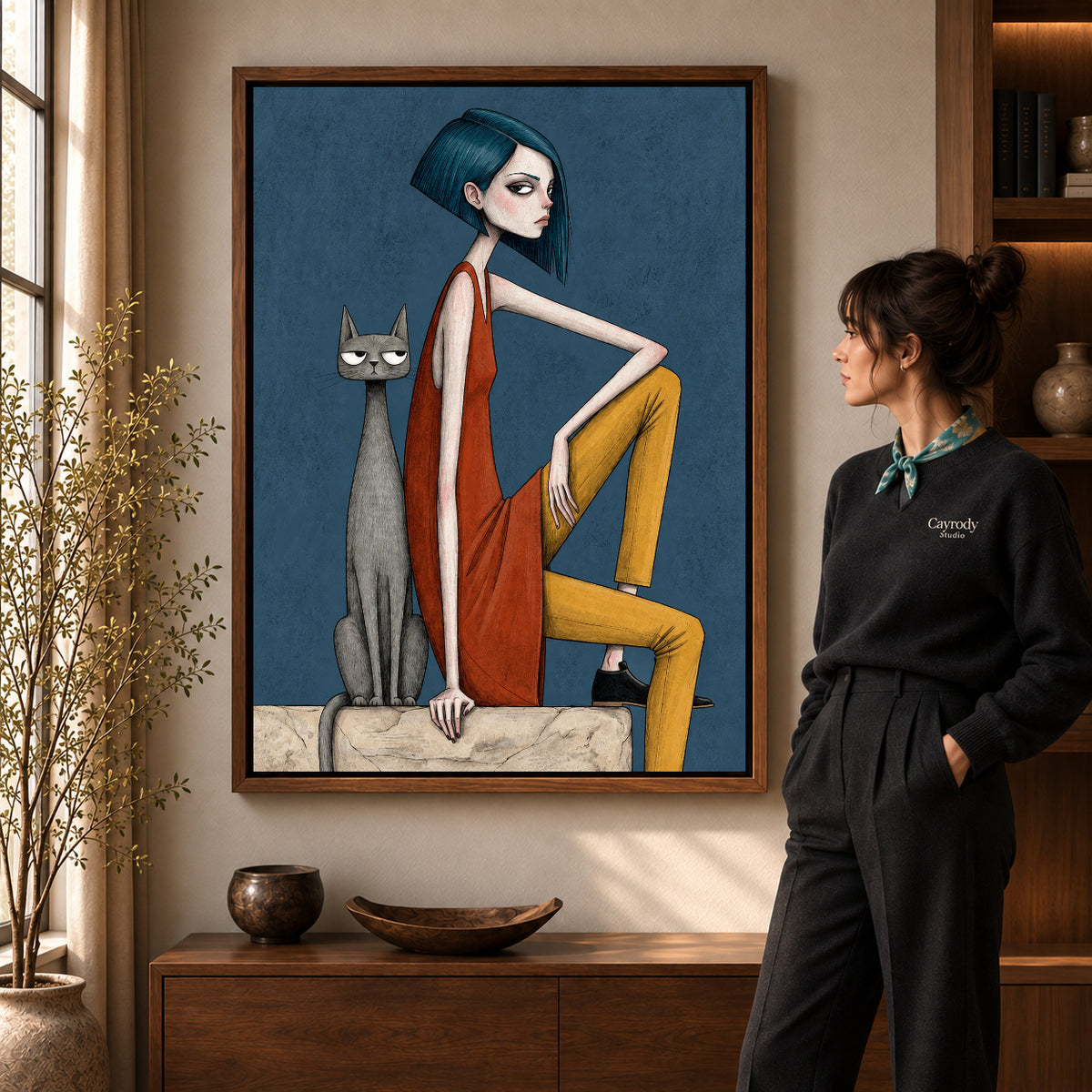 Angular Woman Cat artwork in a walnut frame beside a standing woman in a warm room.
