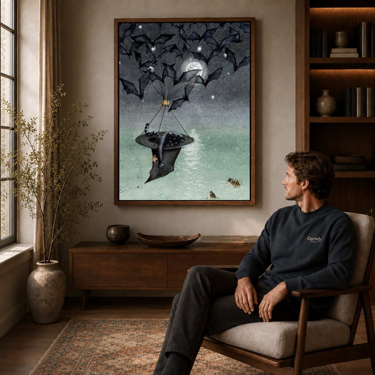 Walnut framed moonlit bat voyage artwork above a seated man in a wood furnished living room.