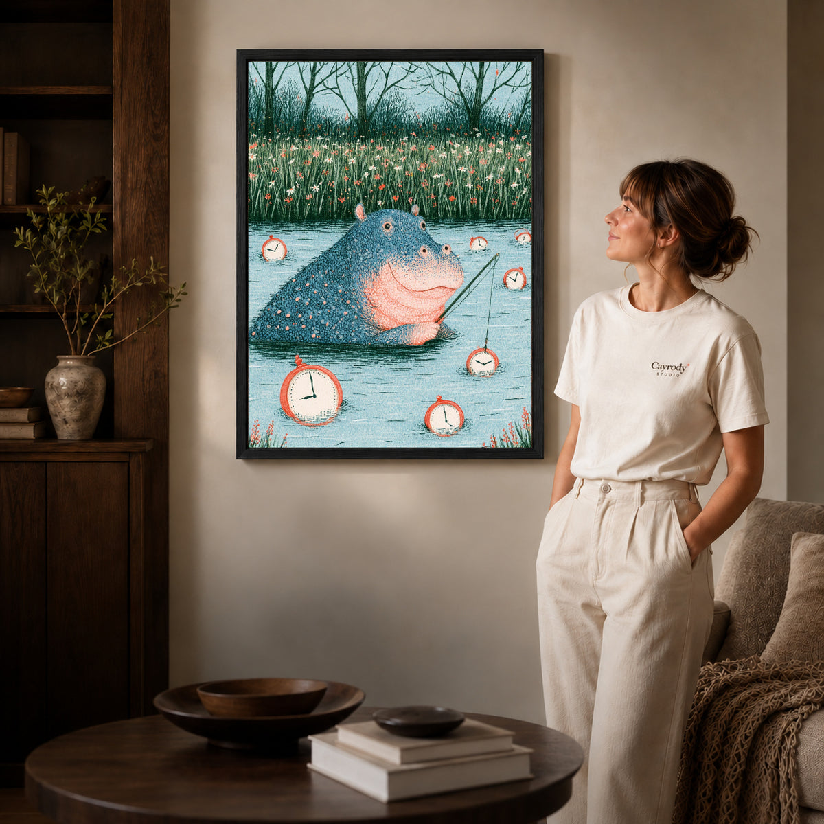 Black framed hippo fishing time artwork beside a woman in a warm neutral living room.