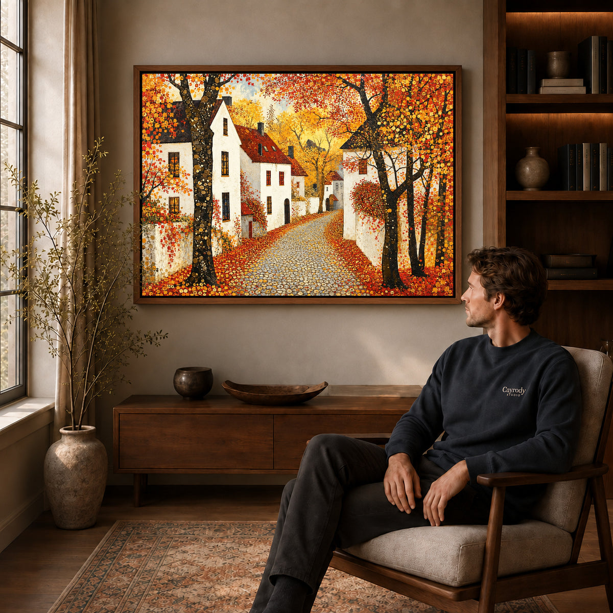 Walnut framed golden village lane artwork above a seated man in a wood furnished living room.