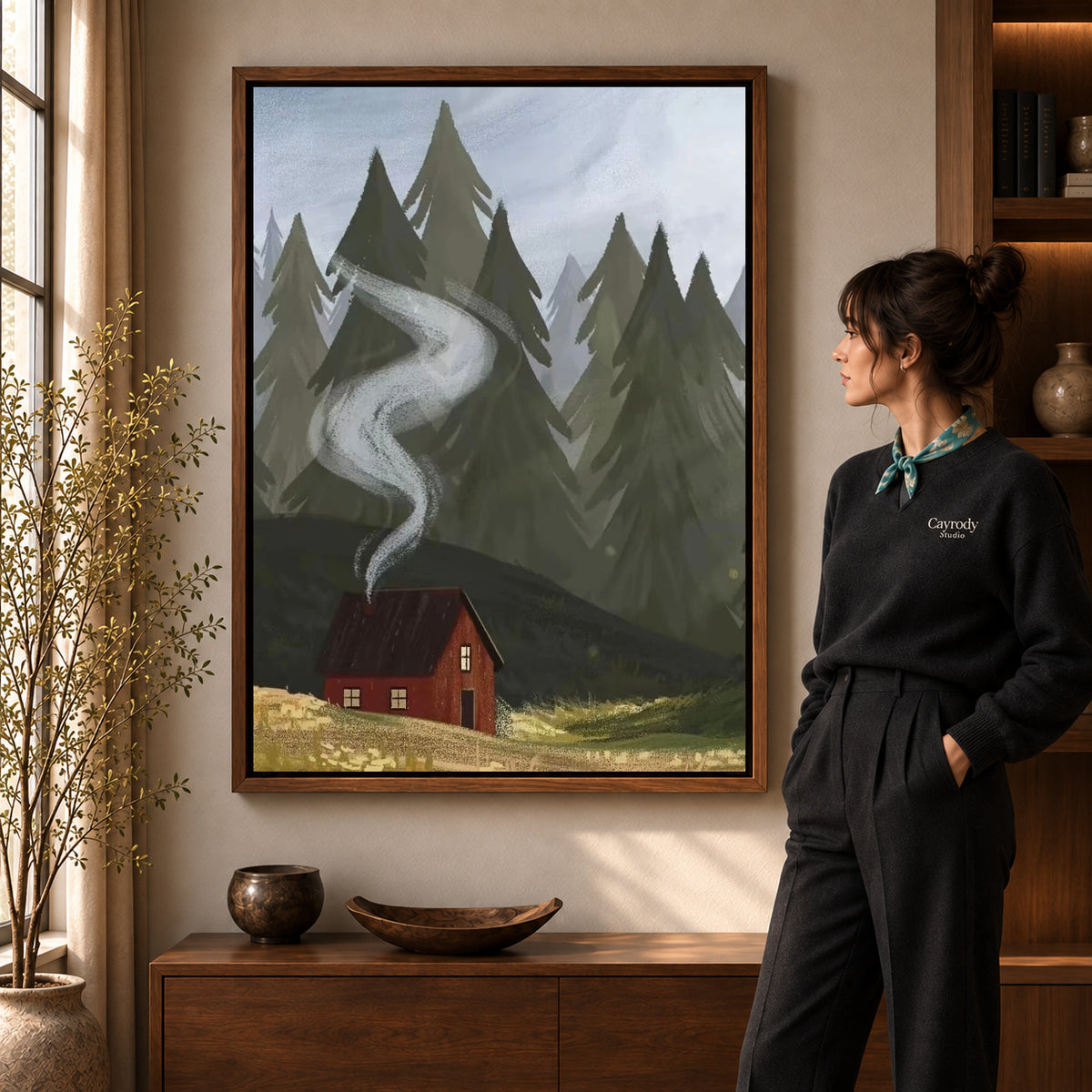 Forest Cabin Smoke artwork in a walnut frame beside a standing woman in a warm room.