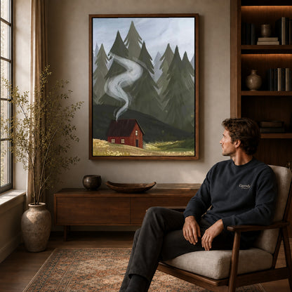 Walnut framed forest cabin smoke artwork above a seated man in a wood furnished living room.