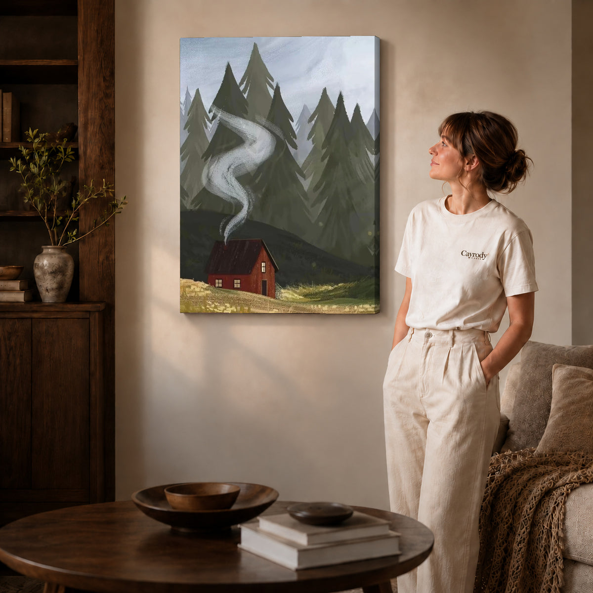 Gallery wrapped forest cabin smoke artwork with shaded canvas edges beside a woman wearing cream clothing.