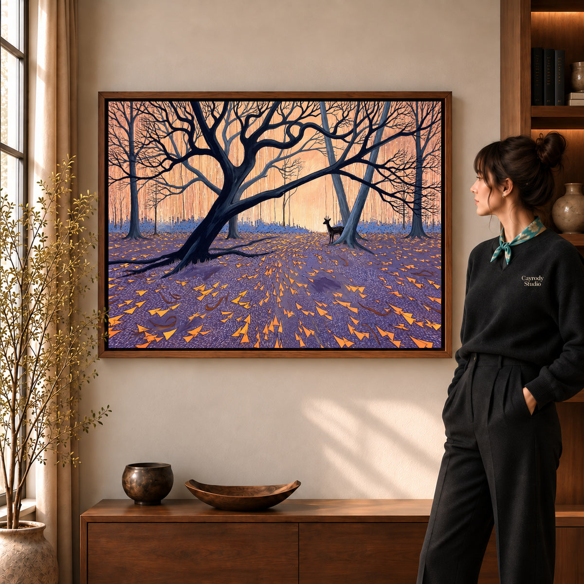 Twilight Forest Deer artwork in a walnut frame beside a standing woman in a warm room.