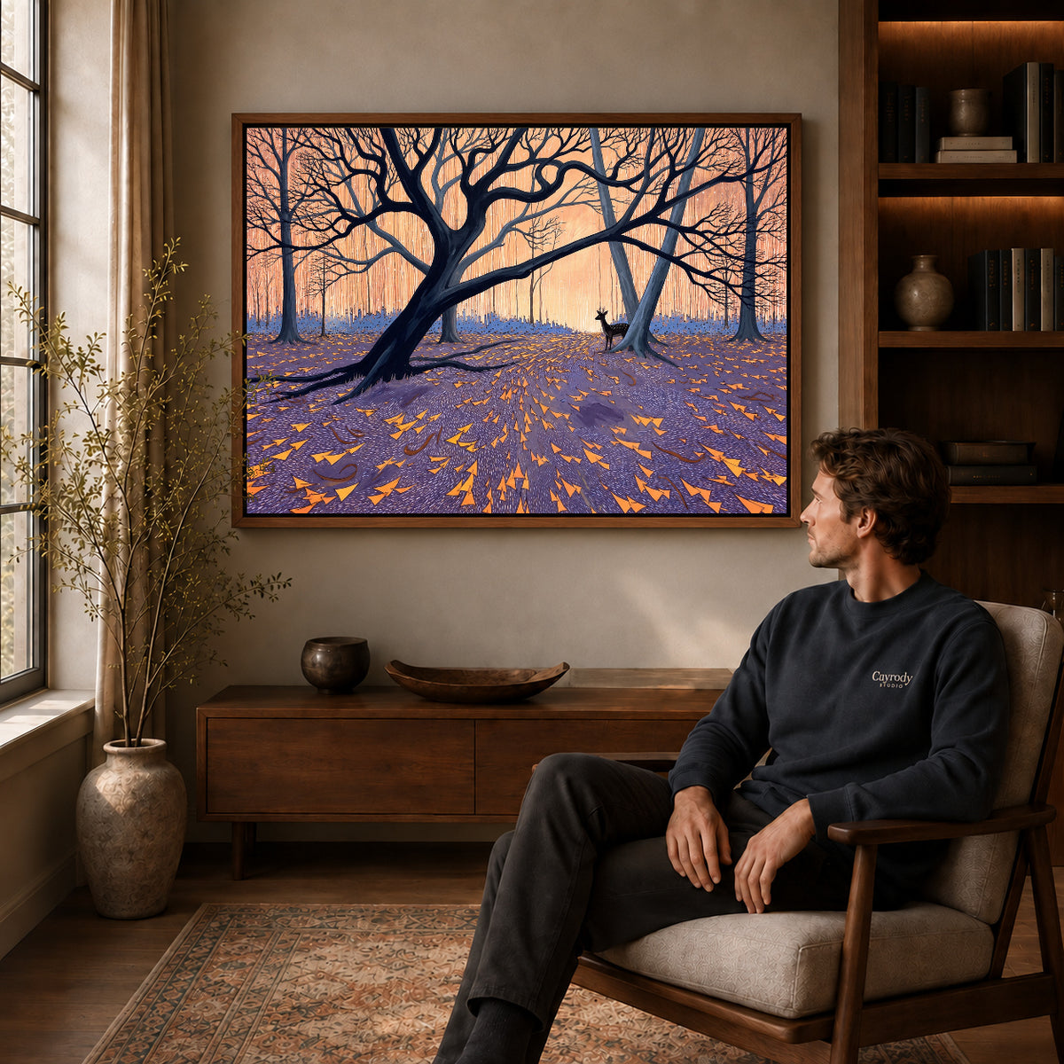 Walnut framed twilight forest deer artwork above a seated man in a wood furnished living room.