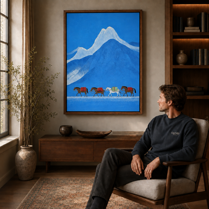 Man relaxing in an armchair beneath framed cobalt blue mountain and horse caravan wall art.