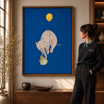 Whimsical elephant canvas wall art in a walnut frame beside a woman in black and a wooden cabinet.